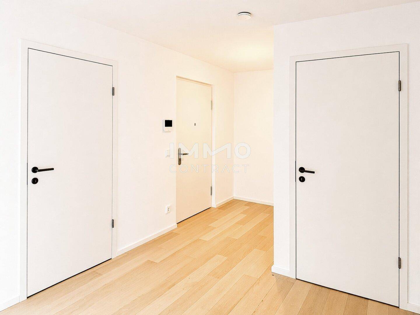 Heller Flur mit modernen weißen Türen und durchgehendem Holzboden.