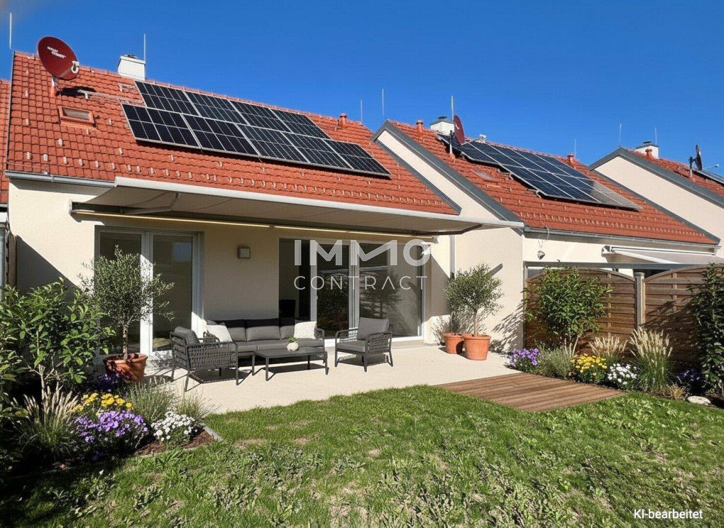 Gepflegter Gartenbereich mit großer Terrasse, bequemen Gartenmöbeln und Photovoltaikanlage auf dem Dach.
