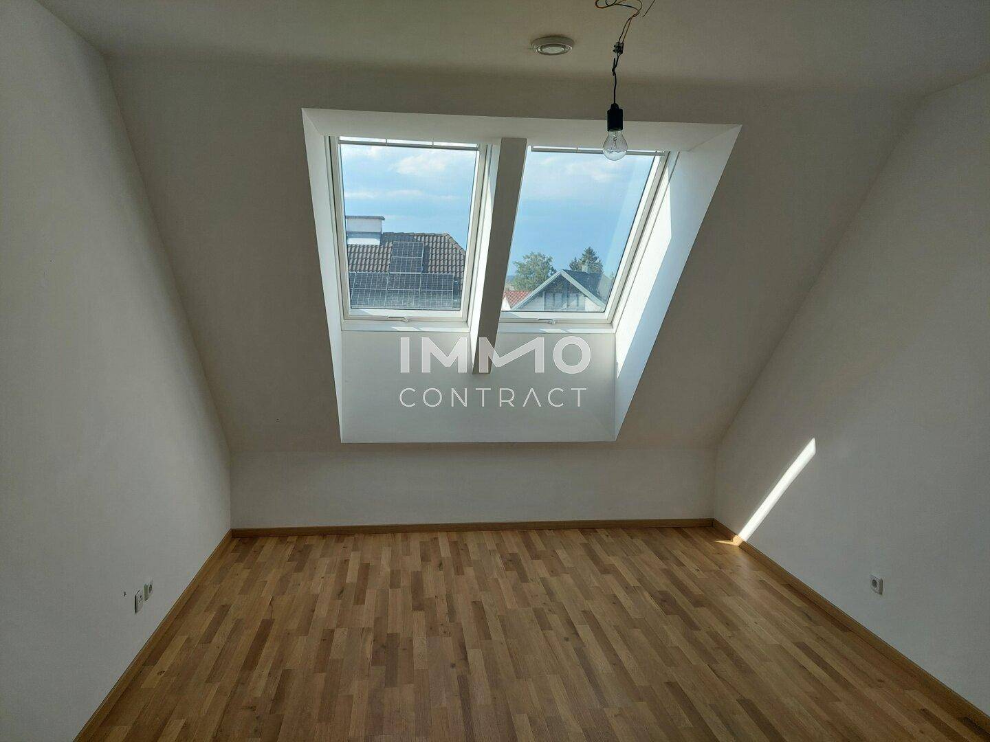 Helles Dachgeschosszimmer mit Parkettboden und zwei großen Dachfenstern.