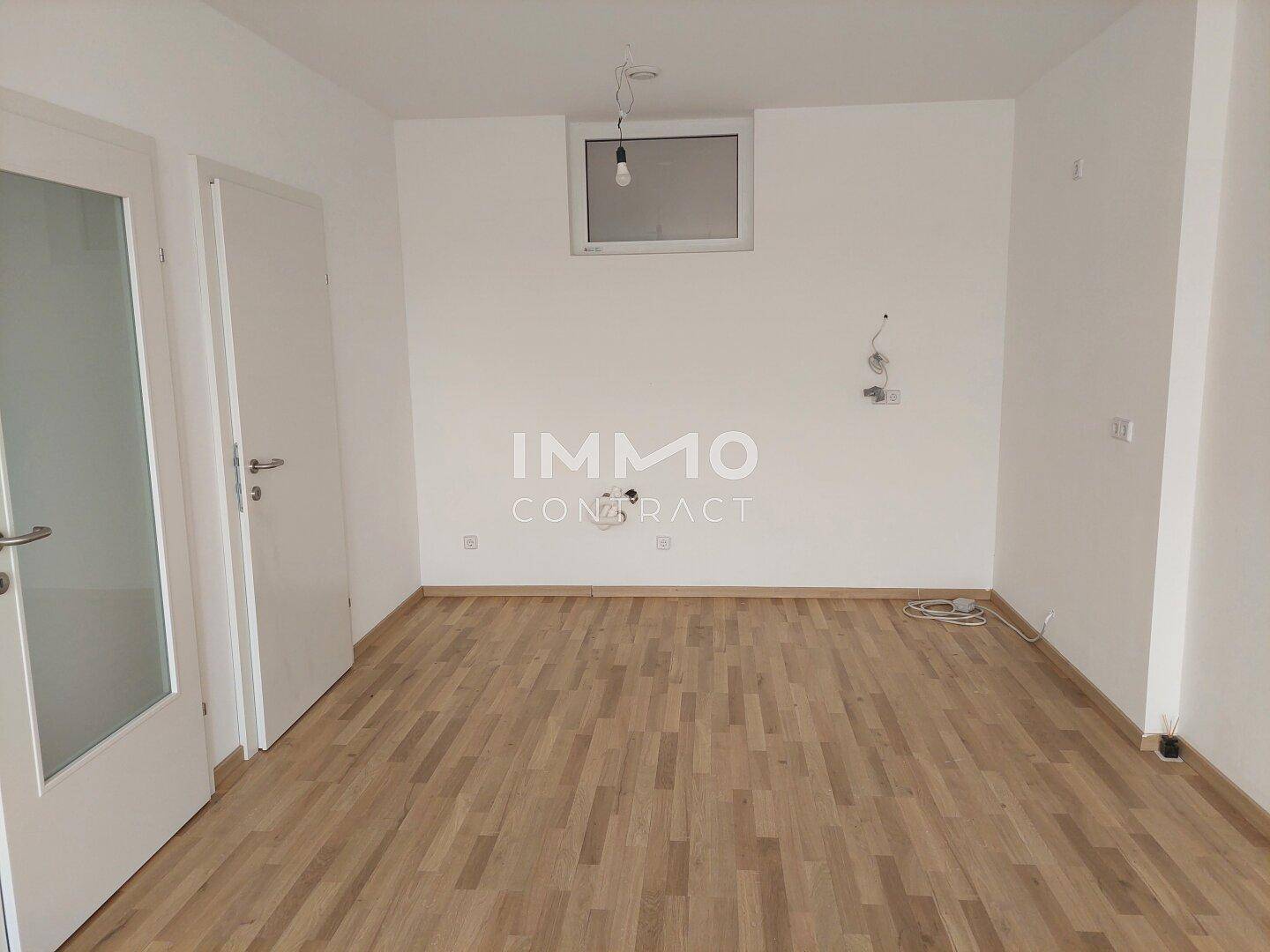 Leerer Raum mit Parkettboden und einem Fenster, vorbereitet für die Installation einer Küche.