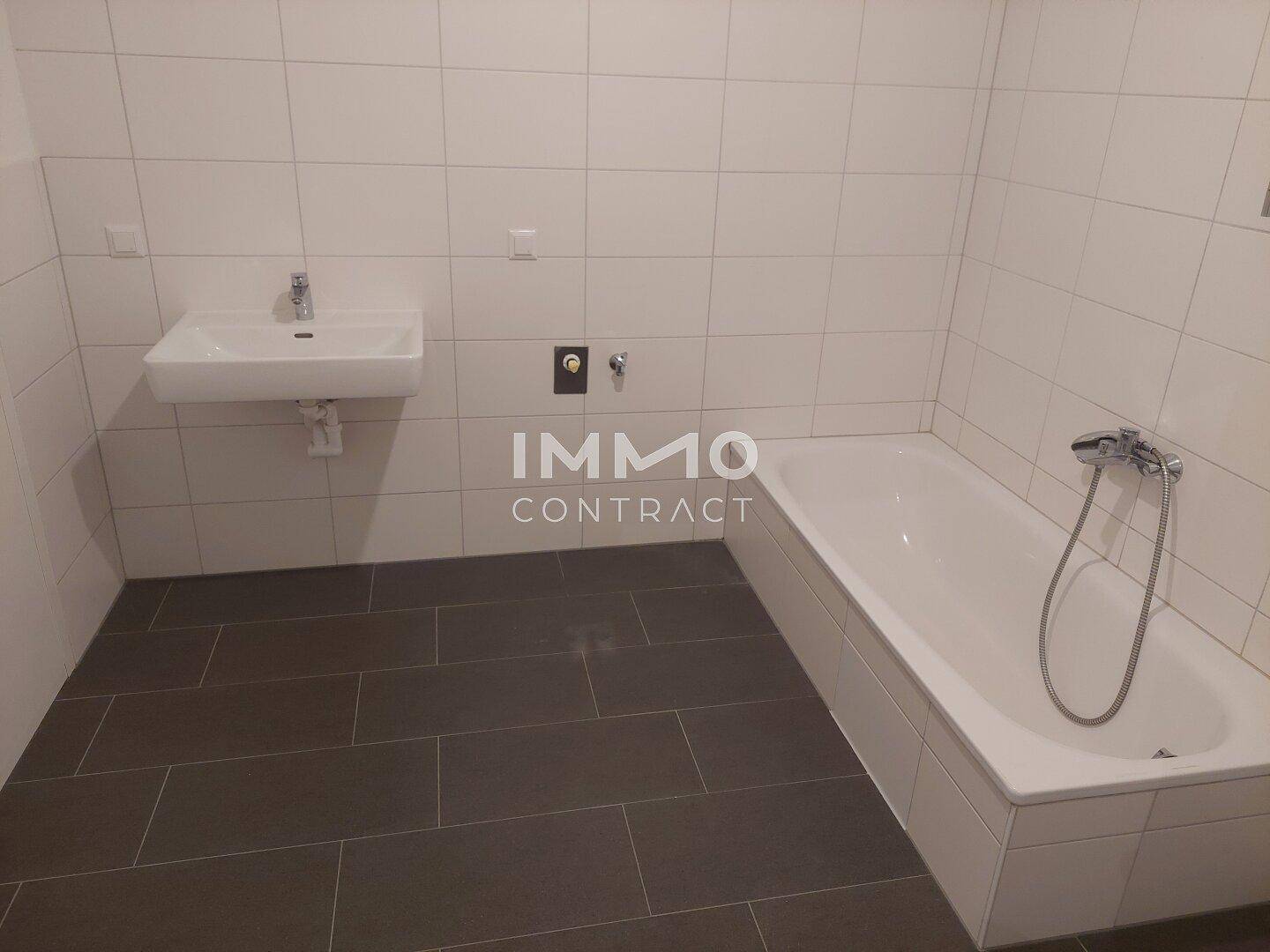 Modernes Badezimmer mit Badewanne, Waschbecken und weißen Wandfliesen.