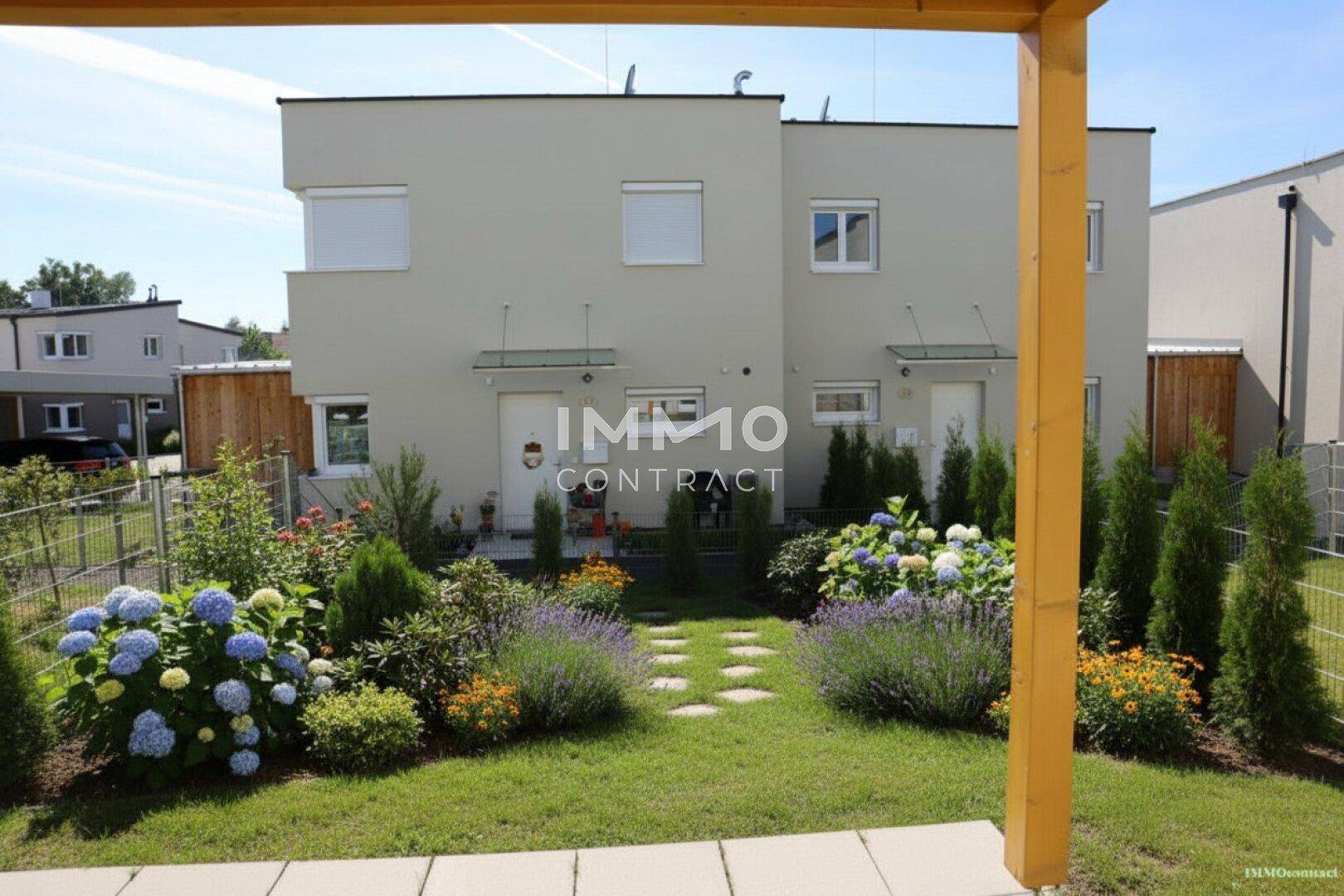 Gepflegter Garten mit Blumenbeeten, Rasenfläche und Blick auf die Doppelhaushälfte.