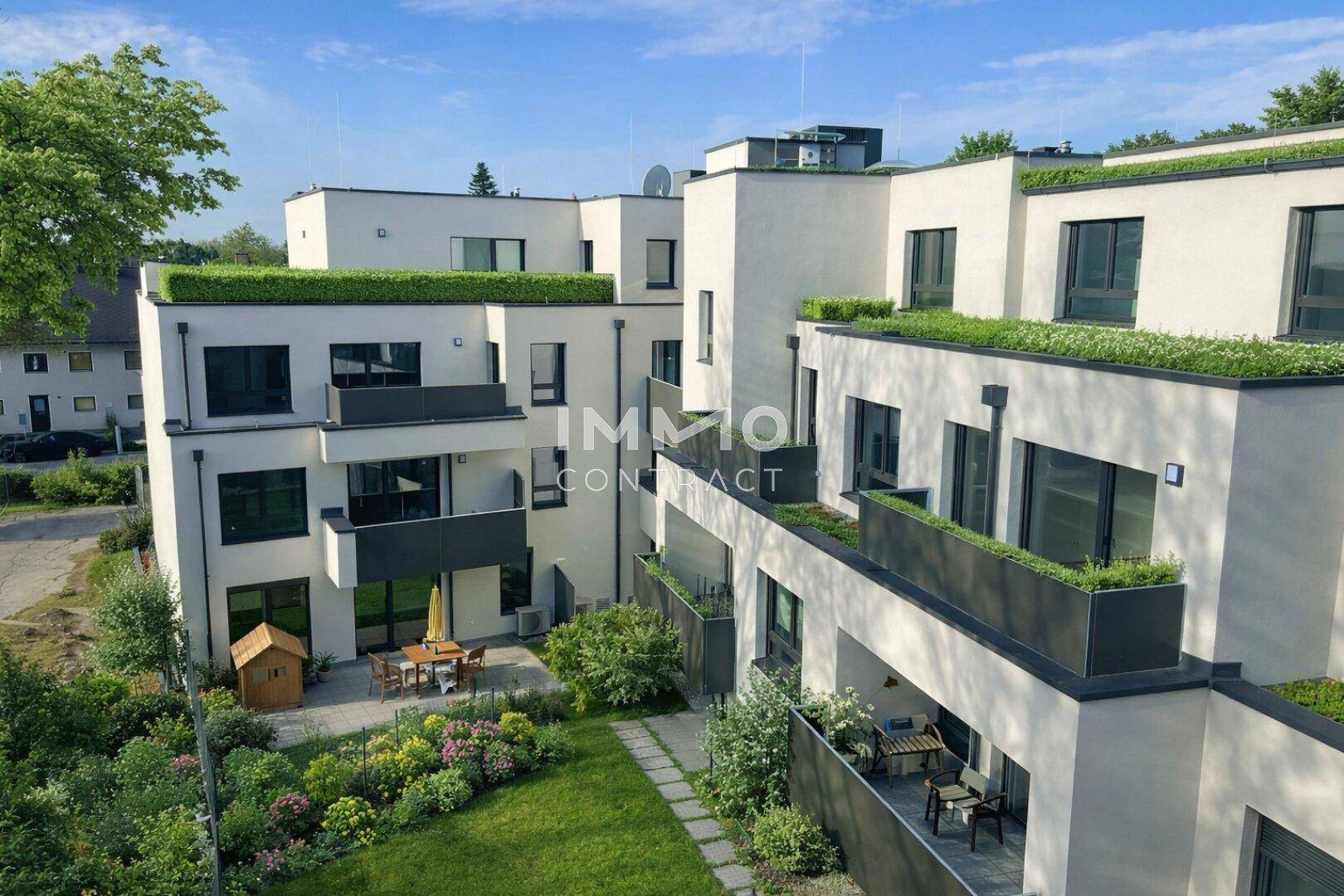 Ansicht einer modernen Wohnanlage mit begrünten Dächern, Balkonen und einem Gemeinschaftsgarten.