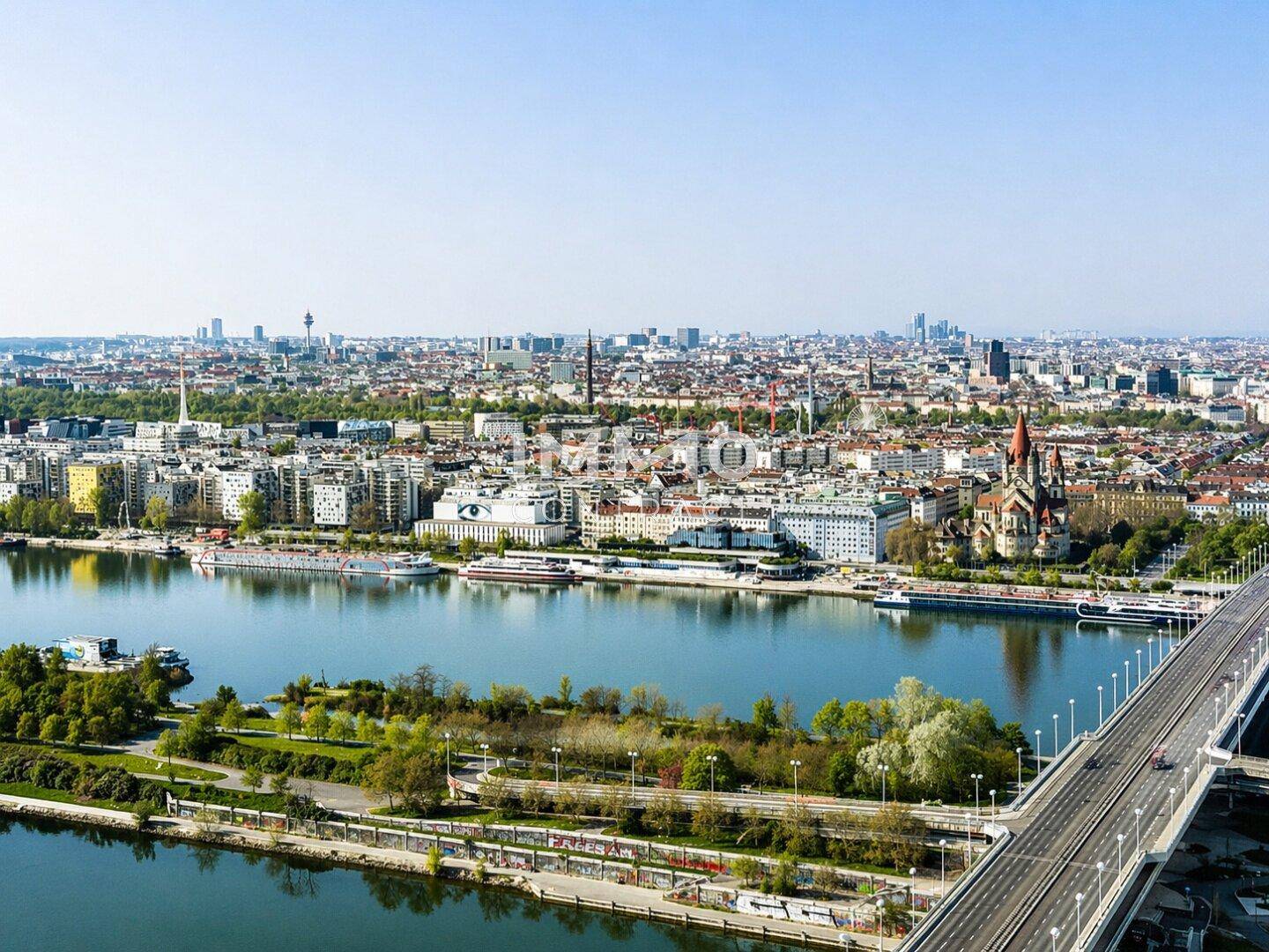 Luftaufnahme der Stadt mit Fluss, Brücke und historischen Gebäuden unter blauem Himmel.