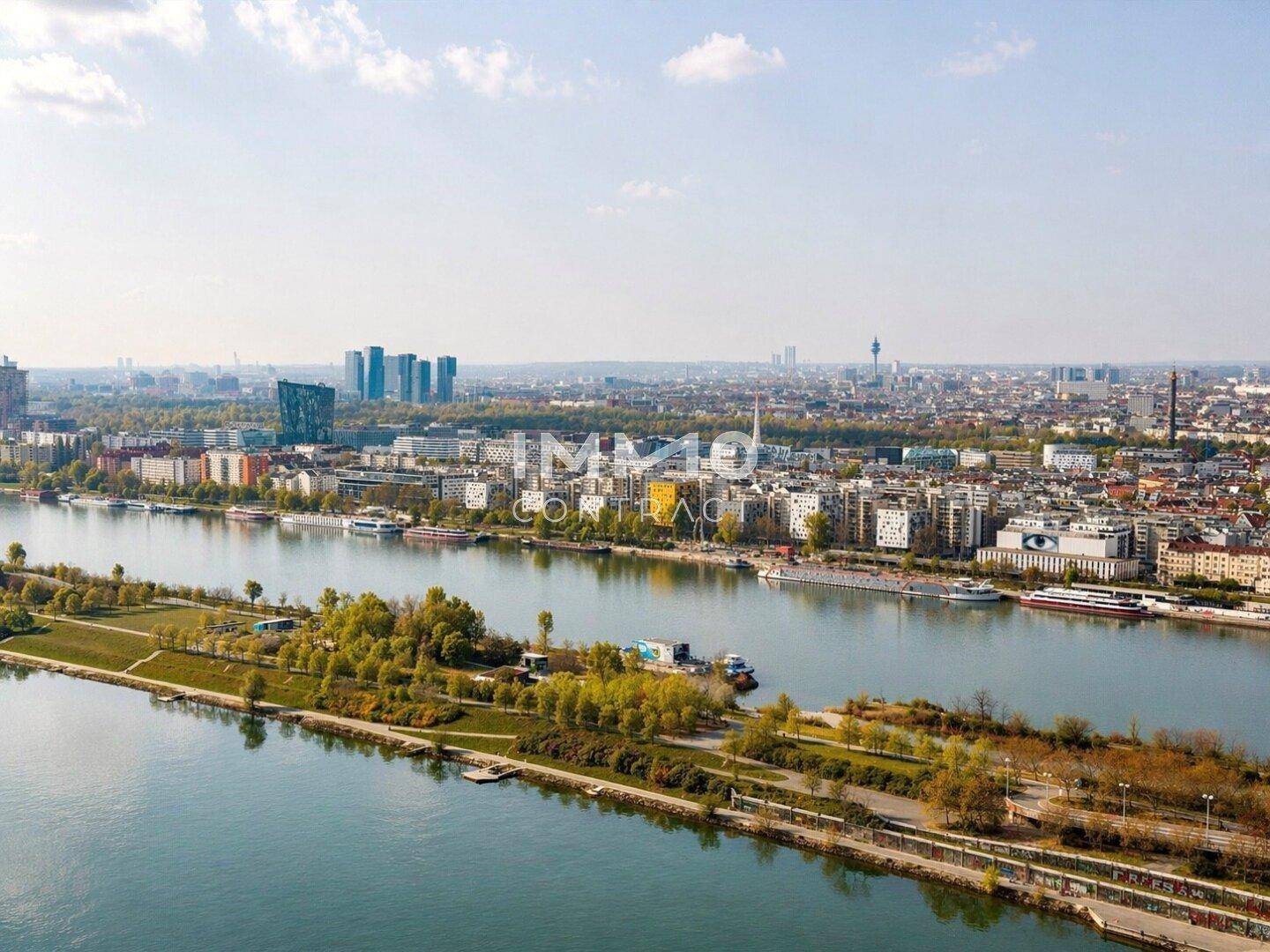 Weitläufiger Blick über die Stadt und den Fluss mit modernen Gebäuden und Grünflächen.