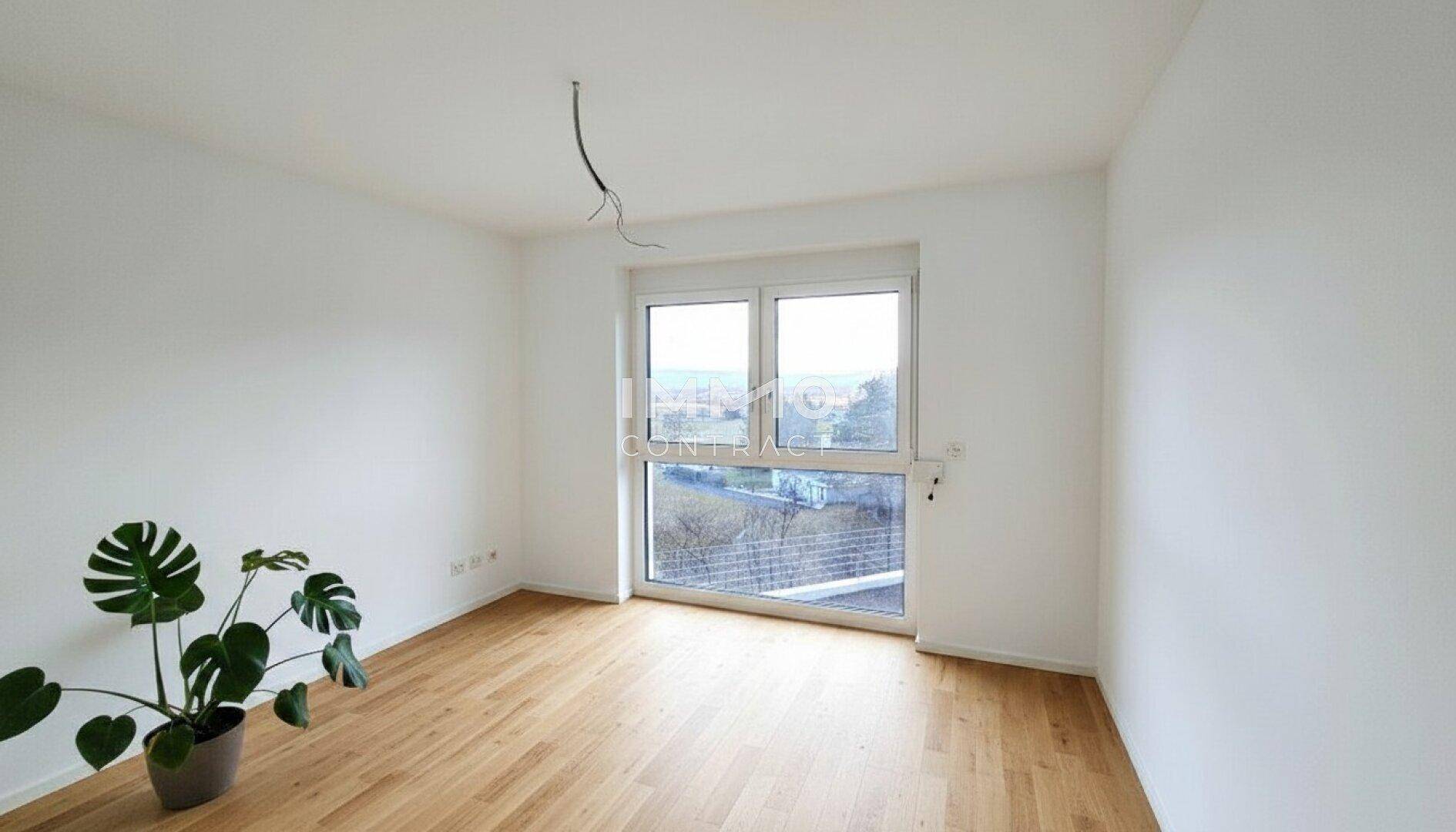 Helles Zimmer mit Holzboden und großem Fenster, das einen weiten Blick auf die Landschaft bietet.
