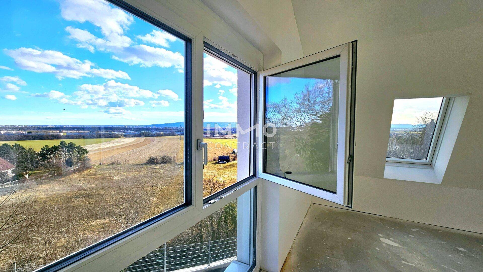 Helles Zimmer mit großem Fenster, das einen weiten Blick auf die umliegende Landschaft bietet.