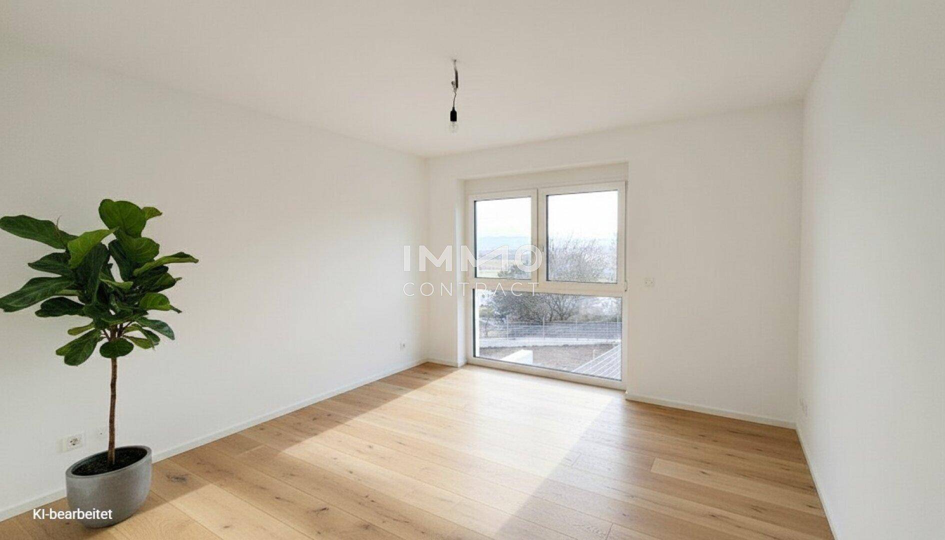 Helles Zimmer mit Holzboden und großem Fenster, das viel Tageslicht hereinlässt.