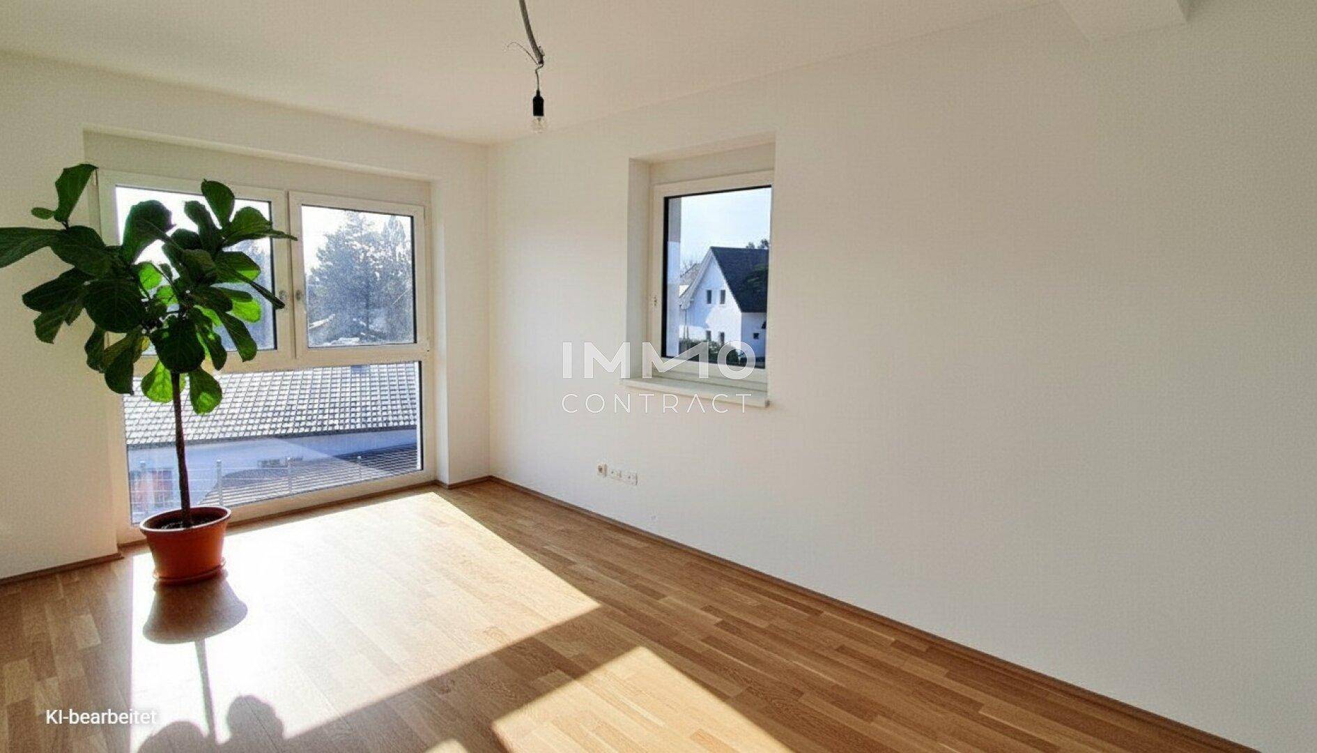 Sonniger Raum mit Holzboden und Blick auf die umliegenden Häuser und Dächer.