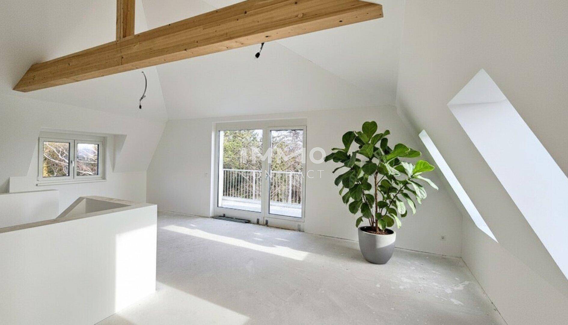 Geräumiger Dachbodenraum mit sichtbaren Holzbalken, Dachschrägen und Zugang zu einem Balkon.