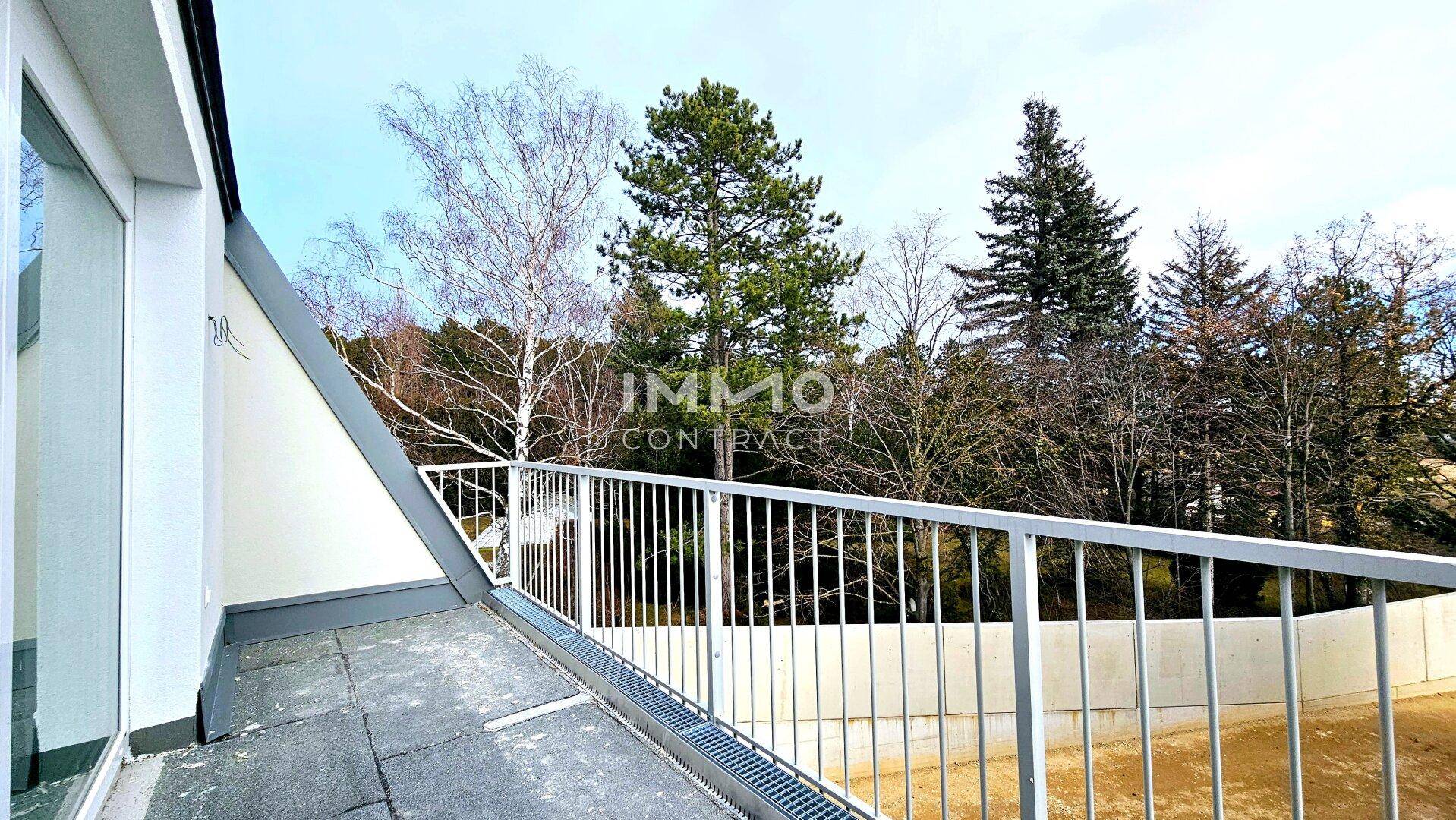Moderner Balkon mit Metallgeländer und Blick auf Bäume und die grüne Umgebung.
