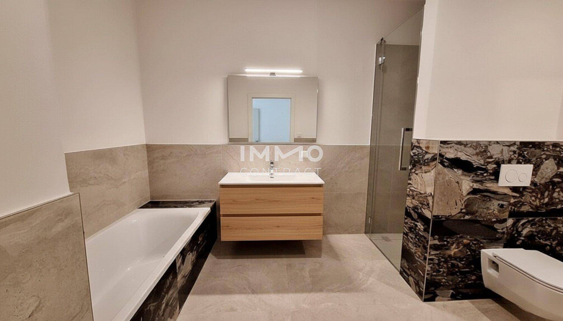 Modernes Badezimmer mit Badewanne, begehbarer Dusche und stilvollen Fliesen in neutralen Farbtönen.