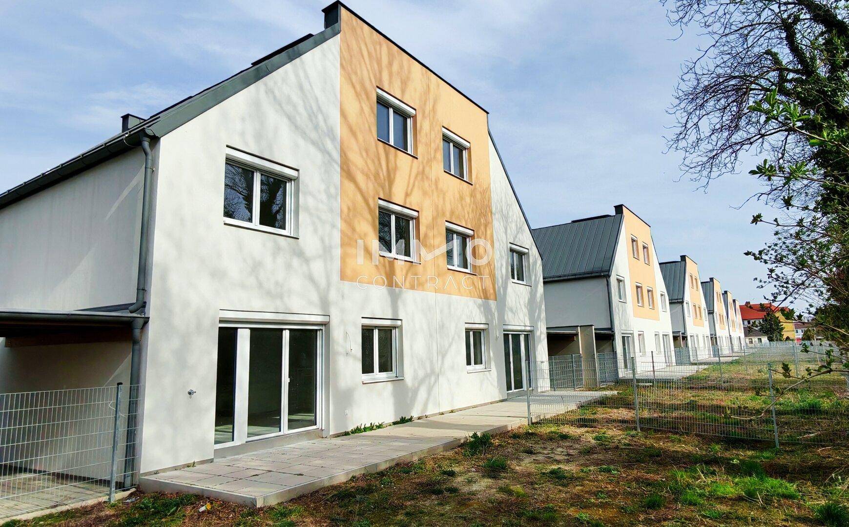 Reihe von modernen Reihenhäusern mit Gärten und einheitlicher Architektur.