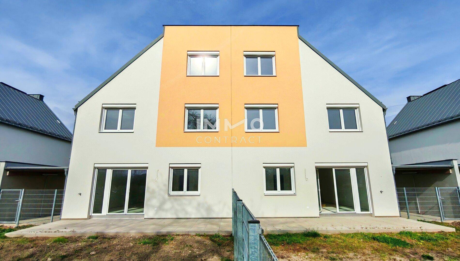 Rückseite der Reihenhäuser mit großen Fenstern und Zugang zu den privaten Gärten.