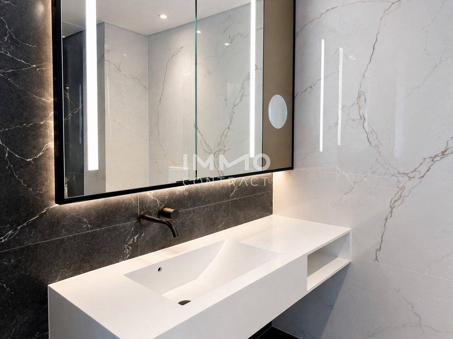 Modernes Badezimmer mit eleganten Marmorfliesen, schwebendem Einzelwaschbecken und beleuchtetem Spiegelschrank.