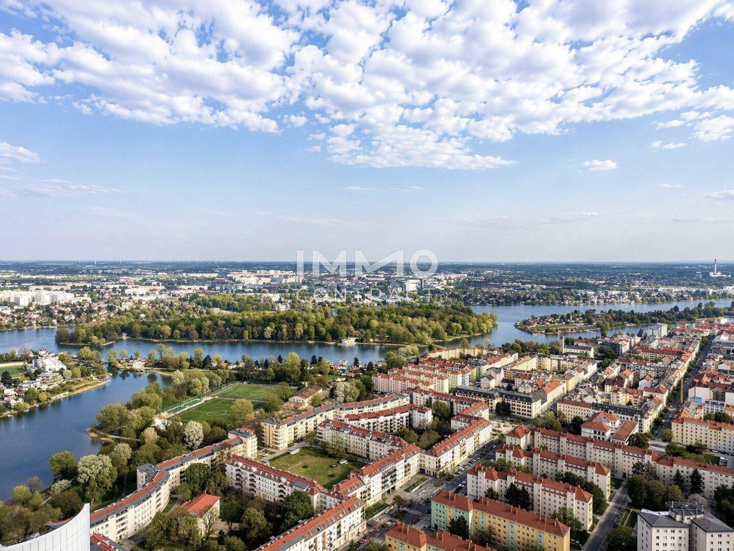 Panoramablick über die Stadt mit mehreren Seen, grünen Inseln und Wohngebieten.