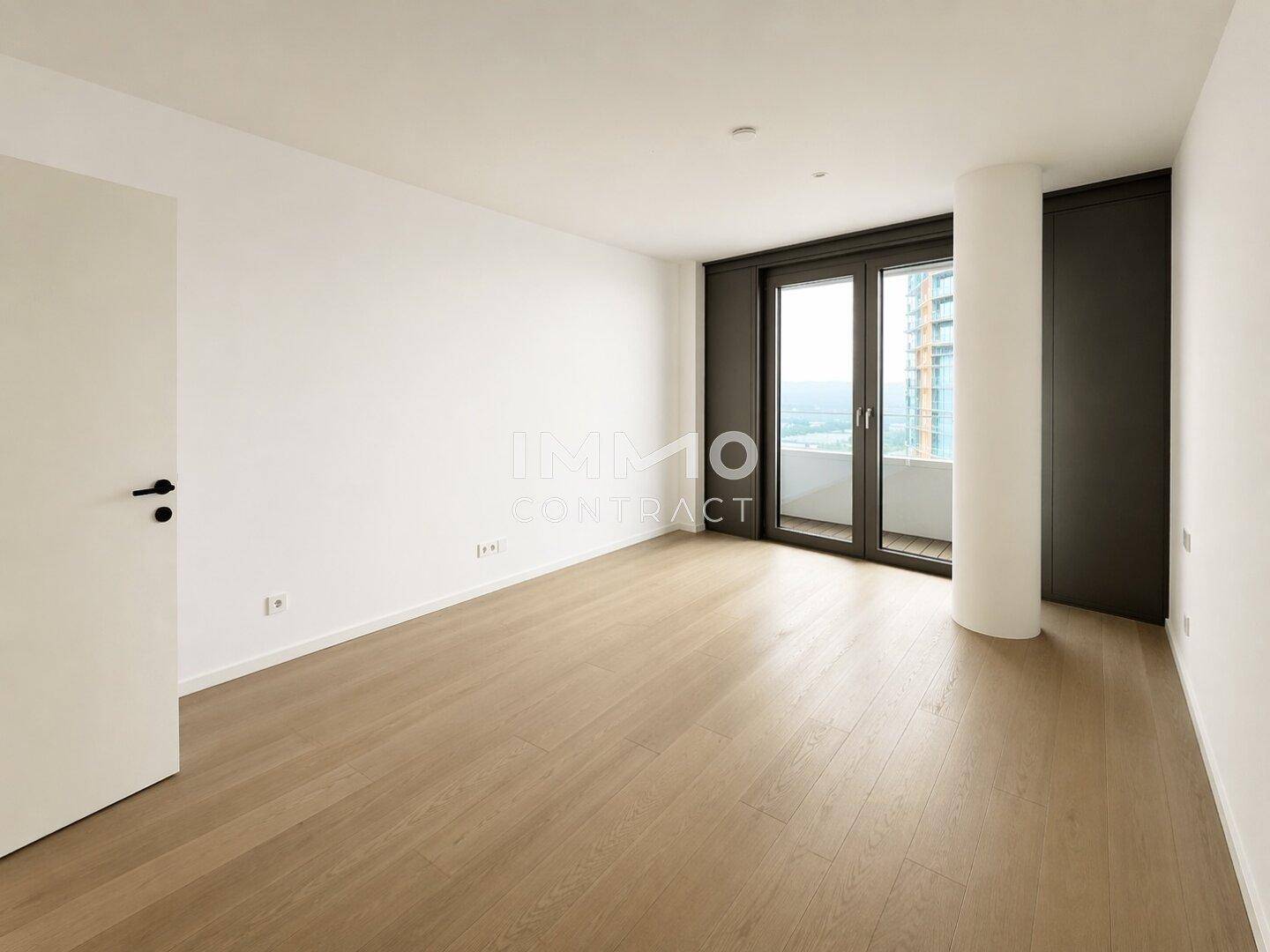 Helles Schlafzimmer mit Holzboden und Zugang zu einem Balkon, der einen weiten Ausblick bietet.