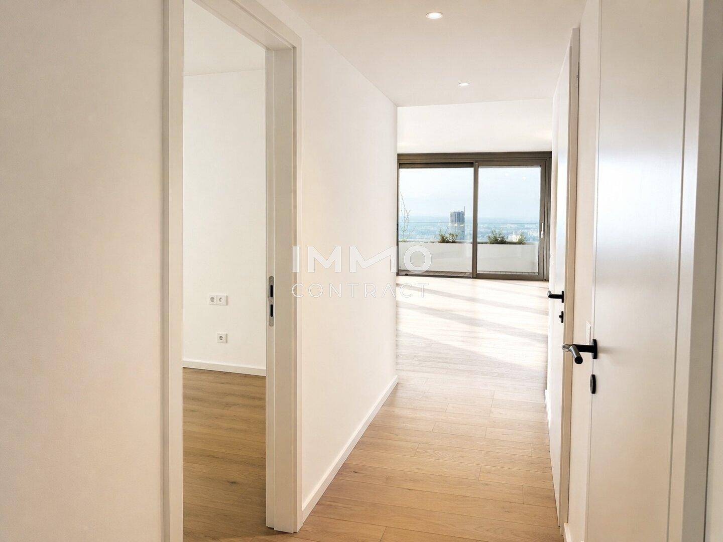 Heller Flur mit Holzboden, der zu weiteren Räumen führt und einen Blick in den Wohnbereich ermöglicht.