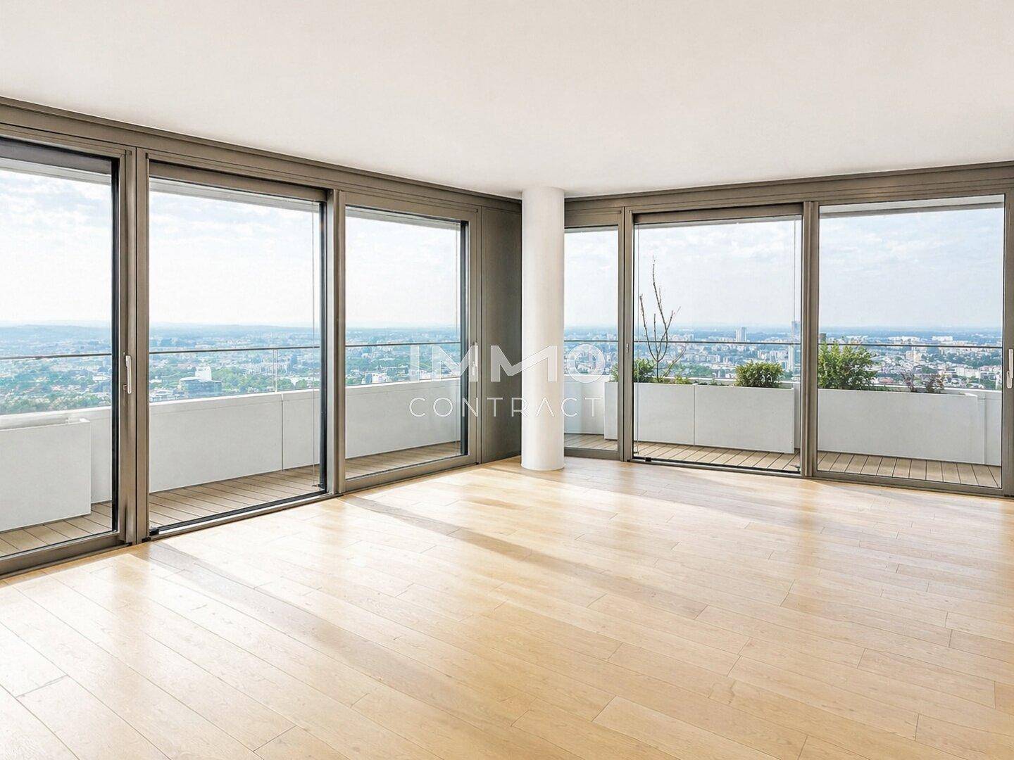 Geräumiges Wohnzimmer mit hellen Holzböden und raumhohen Fenstern, die einen weiten Stadtblick bieten.