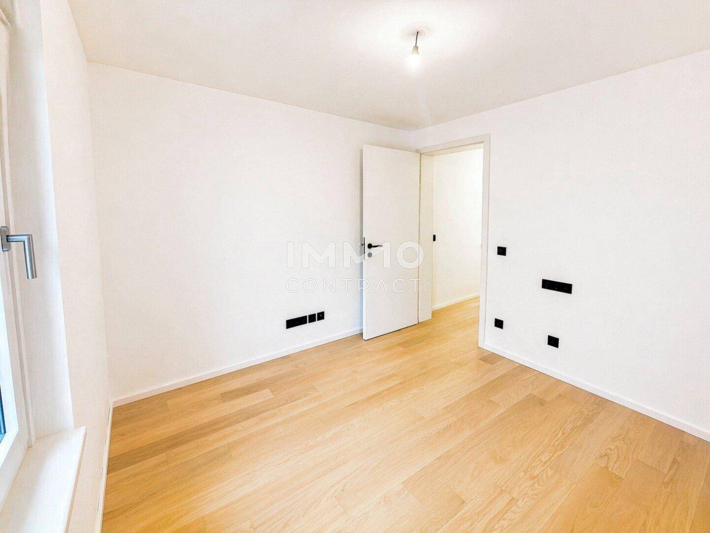 Helles Schlafzimmer mit Holzboden und einem Fenster, das viel Tageslicht hereinlässt.