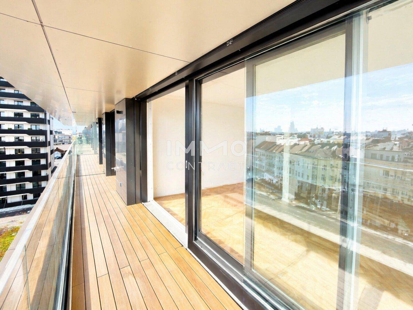 Langer Balkon mit Holzboden und weitem Blick über die Stadt und die umliegenden Gebäude.