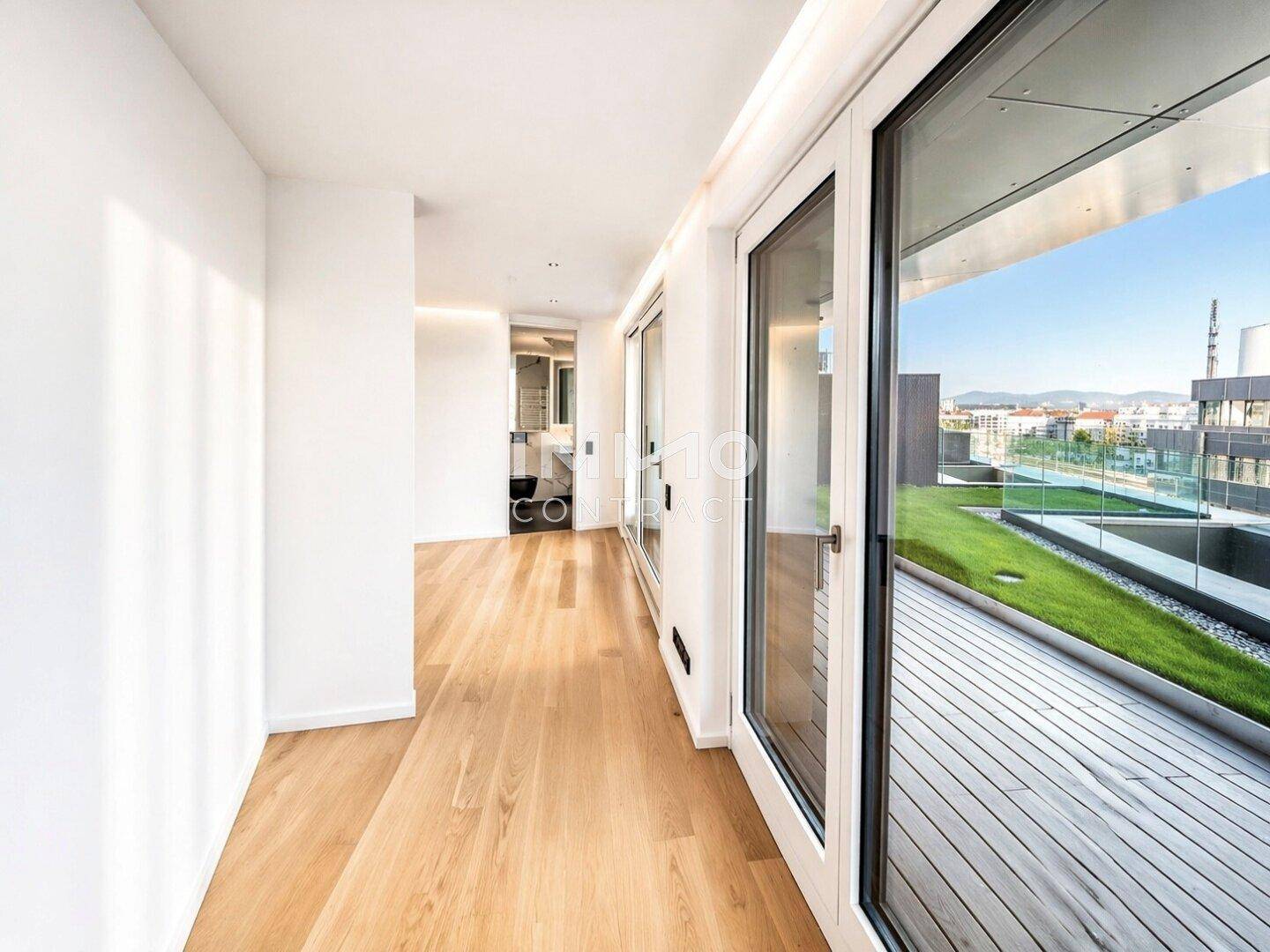 Moderner Flur mit Parkettboden und raumhohen Fenstern, die viel Licht hereinlassen und Zugang zur Terrasse bieten.