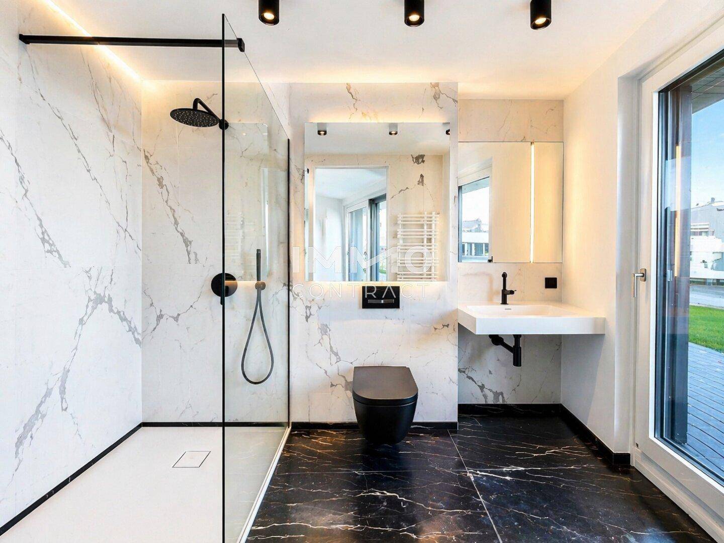 Elegantes Badezimmer mit großformatigen Marmorfliesen, Glasdusche und modernen Armaturen.