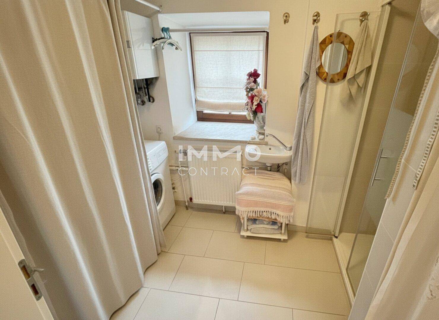 Helles Badezimmer mit Dusche, Waschmaschine und Fenster für natürliche Belüftung.