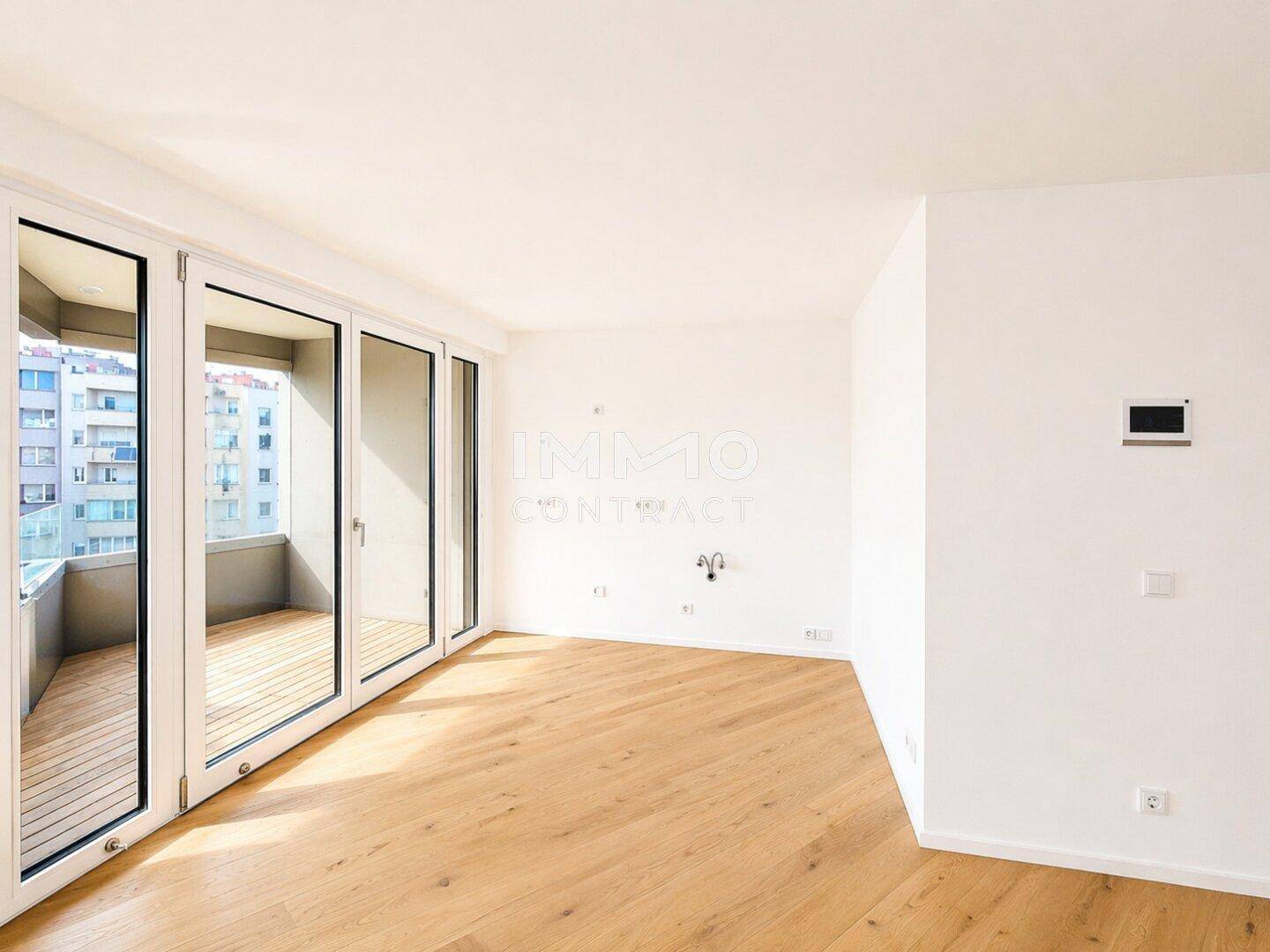 Geräumiger, heller Raum mit Zugang zu einem Balkon und Blick auf die Stadt, ideal für Entspannung.