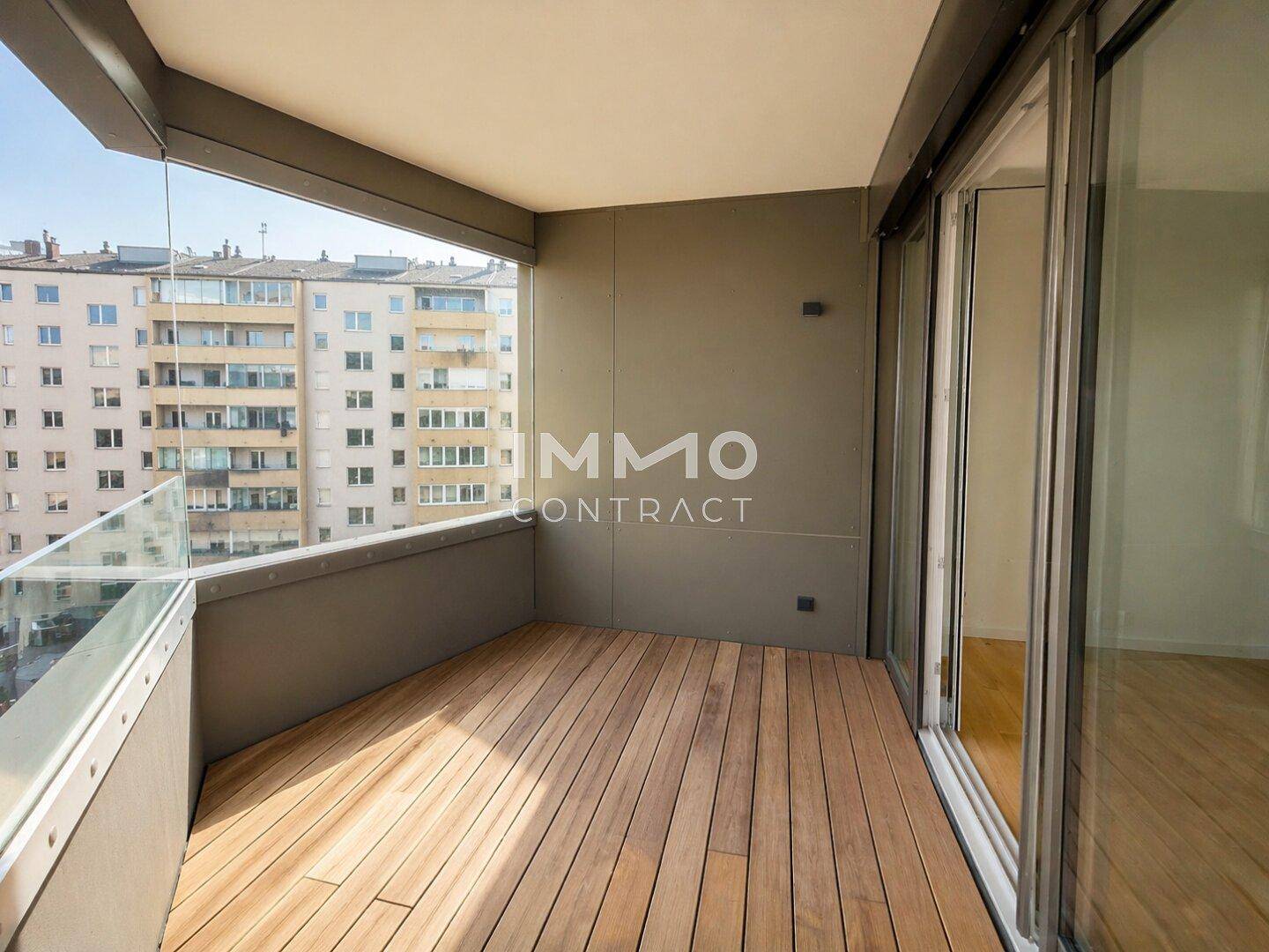 Geräumiger Balkon mit Holzboden und Glasbrüstung, bietet einen weiten Blick über die Stadt.