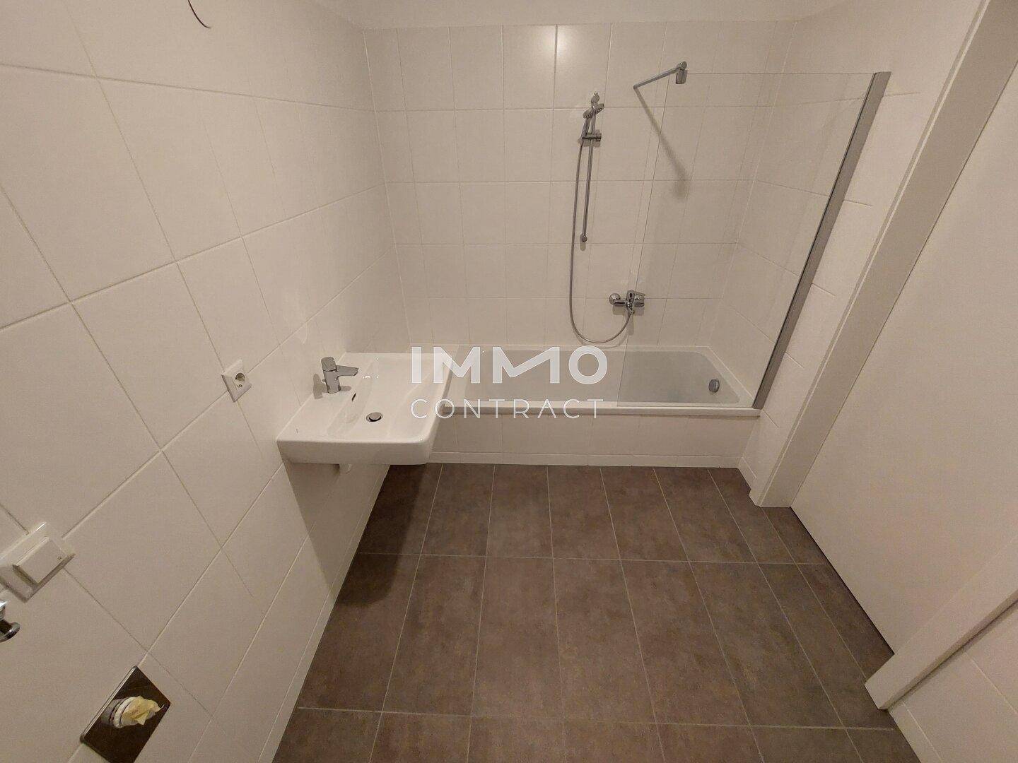 Helles Badezimmer mit Badewanne, Duscharmatur und einem modernen Waschbecken.