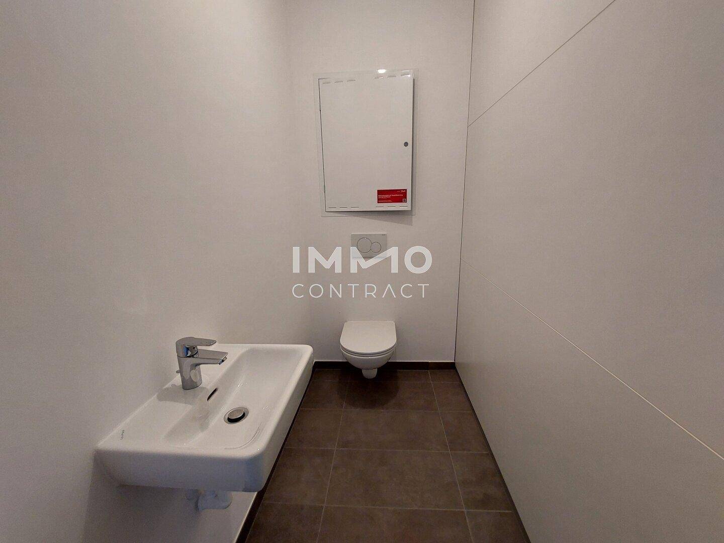 Separates Gäste-WC mit wandhängender Toilette und kleinem Waschbecken.
