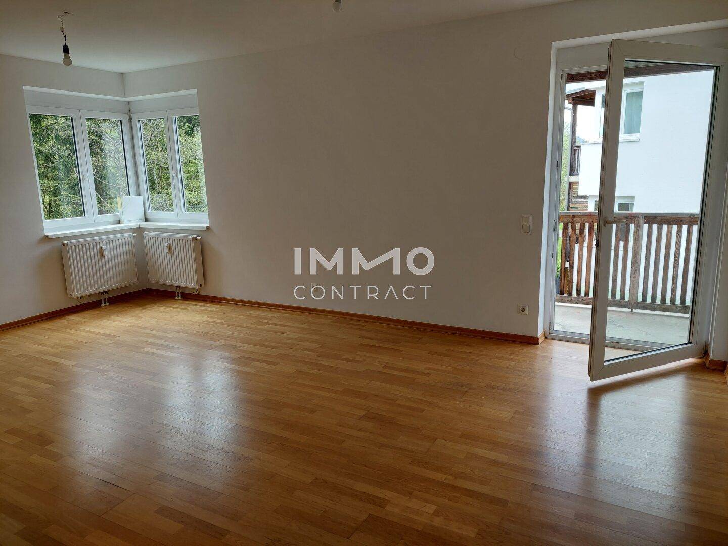 Helles Wohnzimmer mit Parkettboden und Zugang zu einem Balkon, ideal für entspannte Stunden.