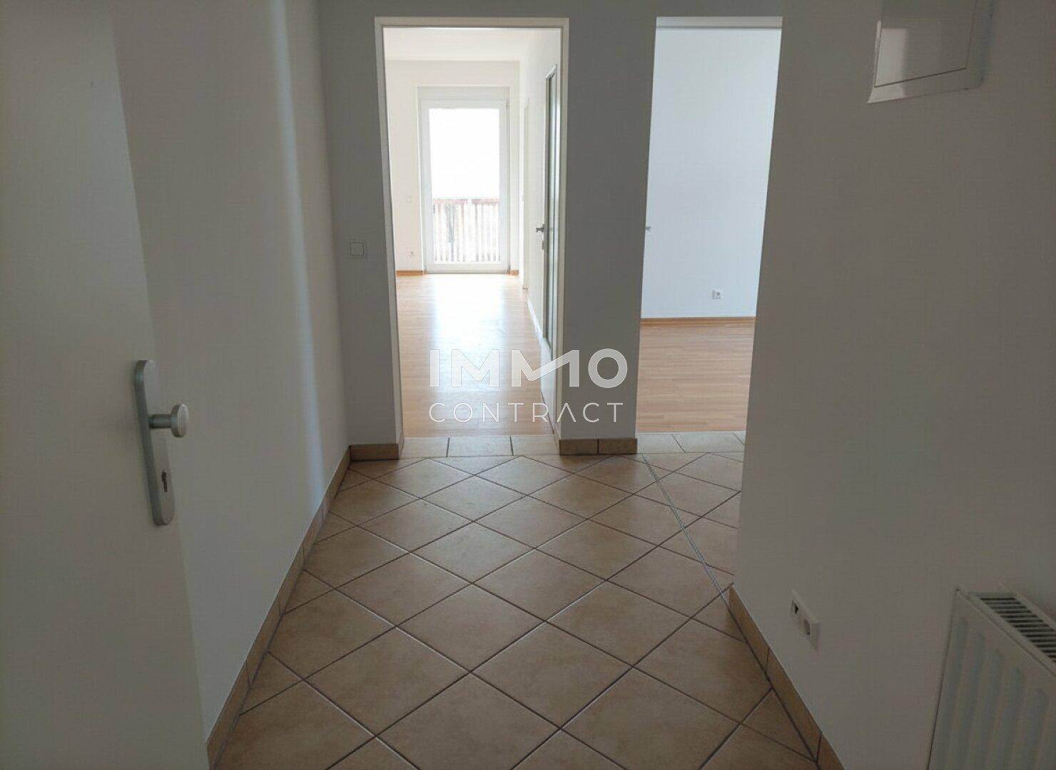 Flur mit Fliesenboden, der zu den Wohnbereichen und dem Balkon führt.