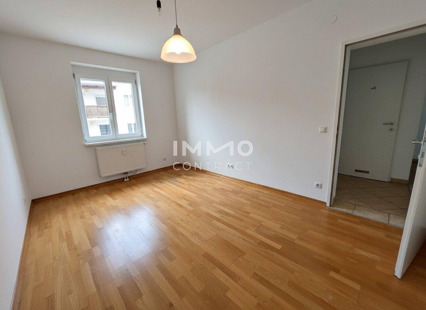 Leeres Zimmer mit Parkettboden und Fenster, geeignet als Schlaf- oder Arbeitszimmer.