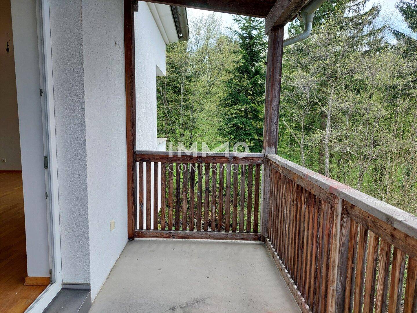 Geräumiger Balkon mit Holzgeländer und Blick ins Grüne, ideal zum Entspannen.