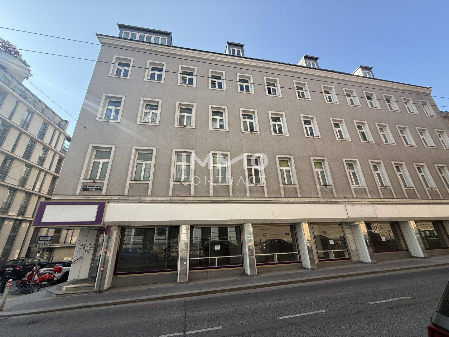 Nahaufnahme der Fassade des Gebäudes mit vielen Fenstern und dem Eingangsbereich der Geschäftsflächen.