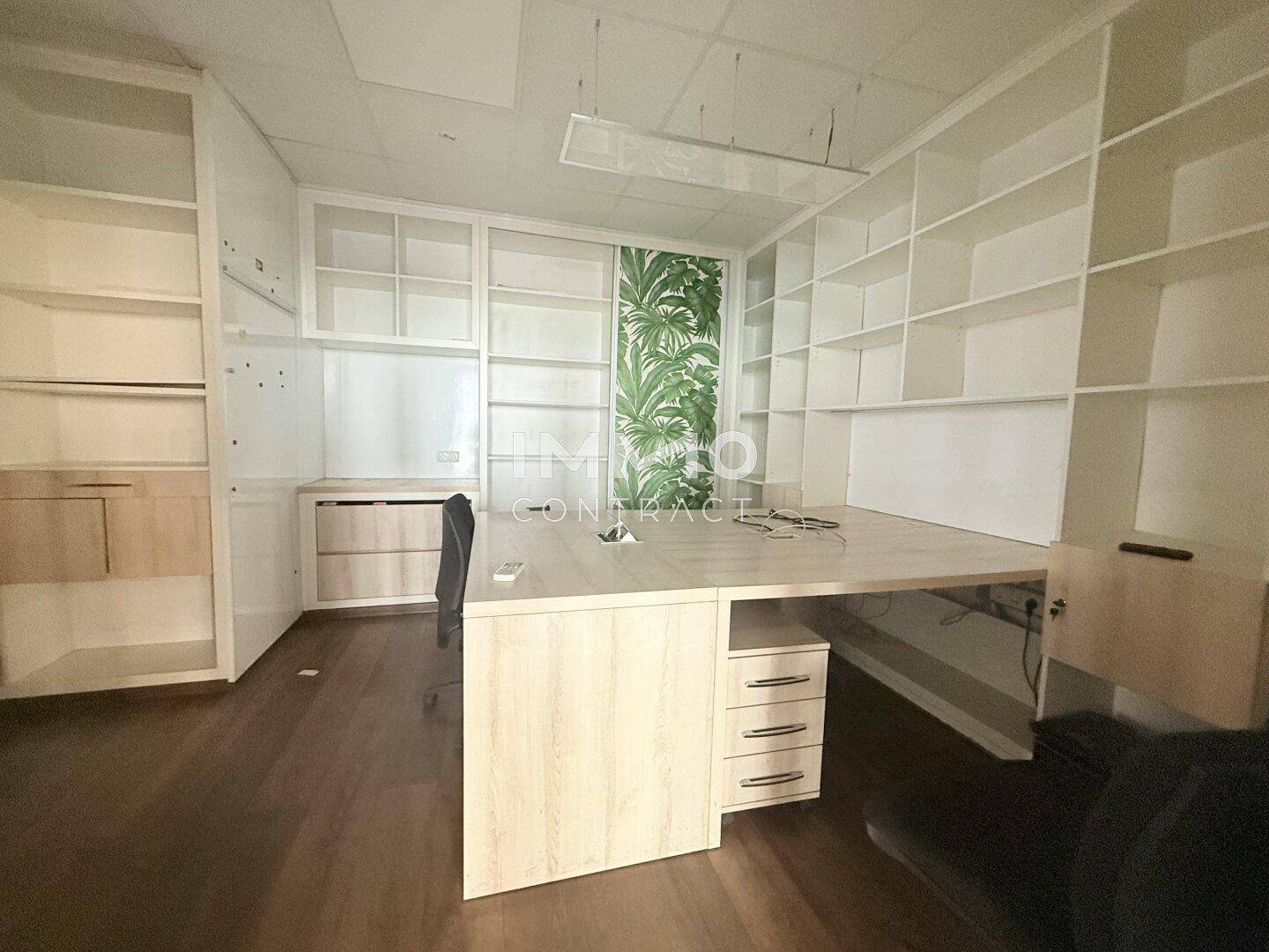 Büroraum mit eingebauten Regalen, Schreibtisch und einem dekorativen Wandbild im Hintergrund.