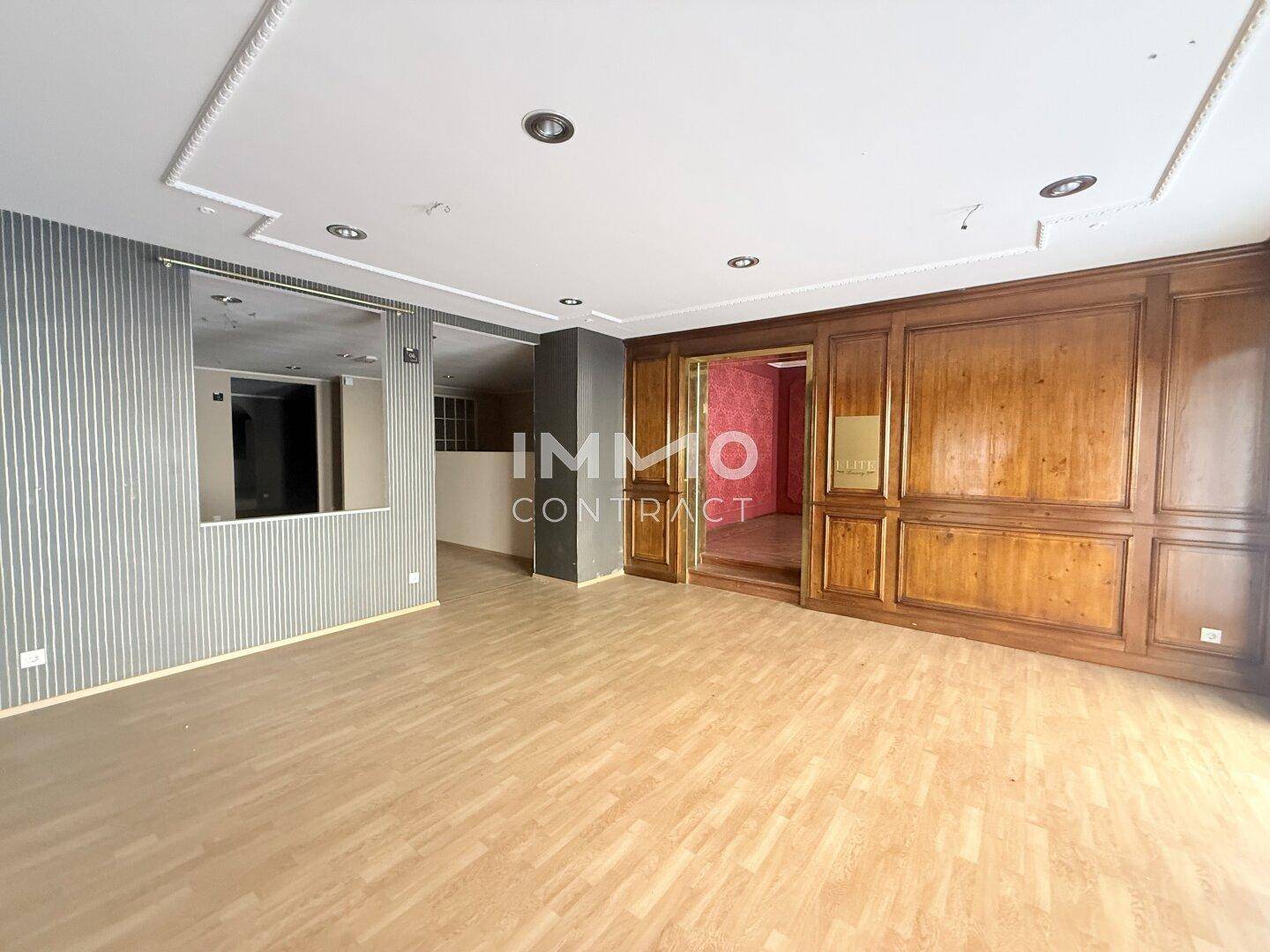 Großer Geschäftsraum mit Holztäfelung und modernem Holzboden, bereit zur individuellen Gestaltung.