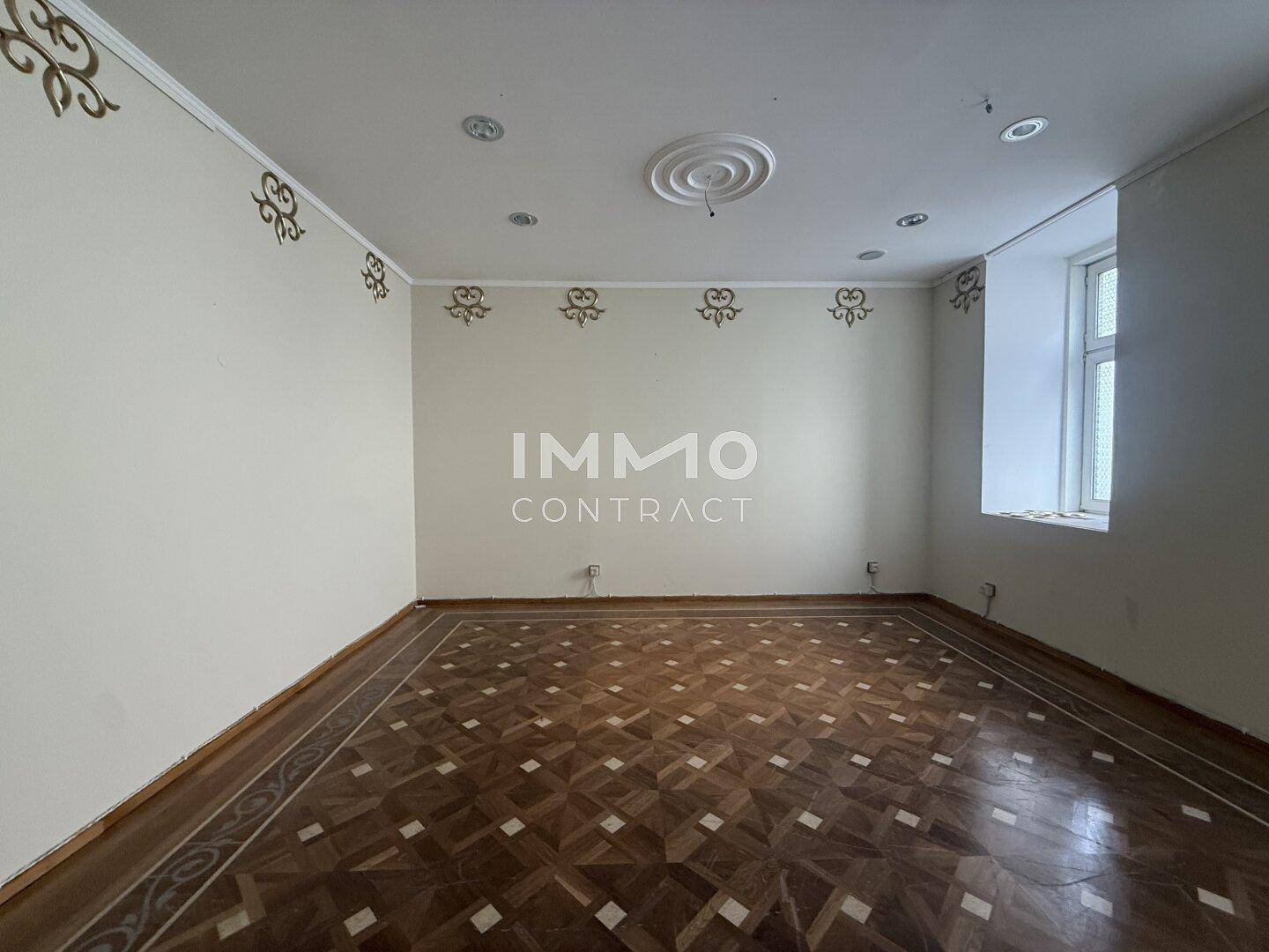 Heller Raum mit klassischem Parkettboden und dezenten Wandverzierungen, der eine ruhige Atmosphäre bietet.