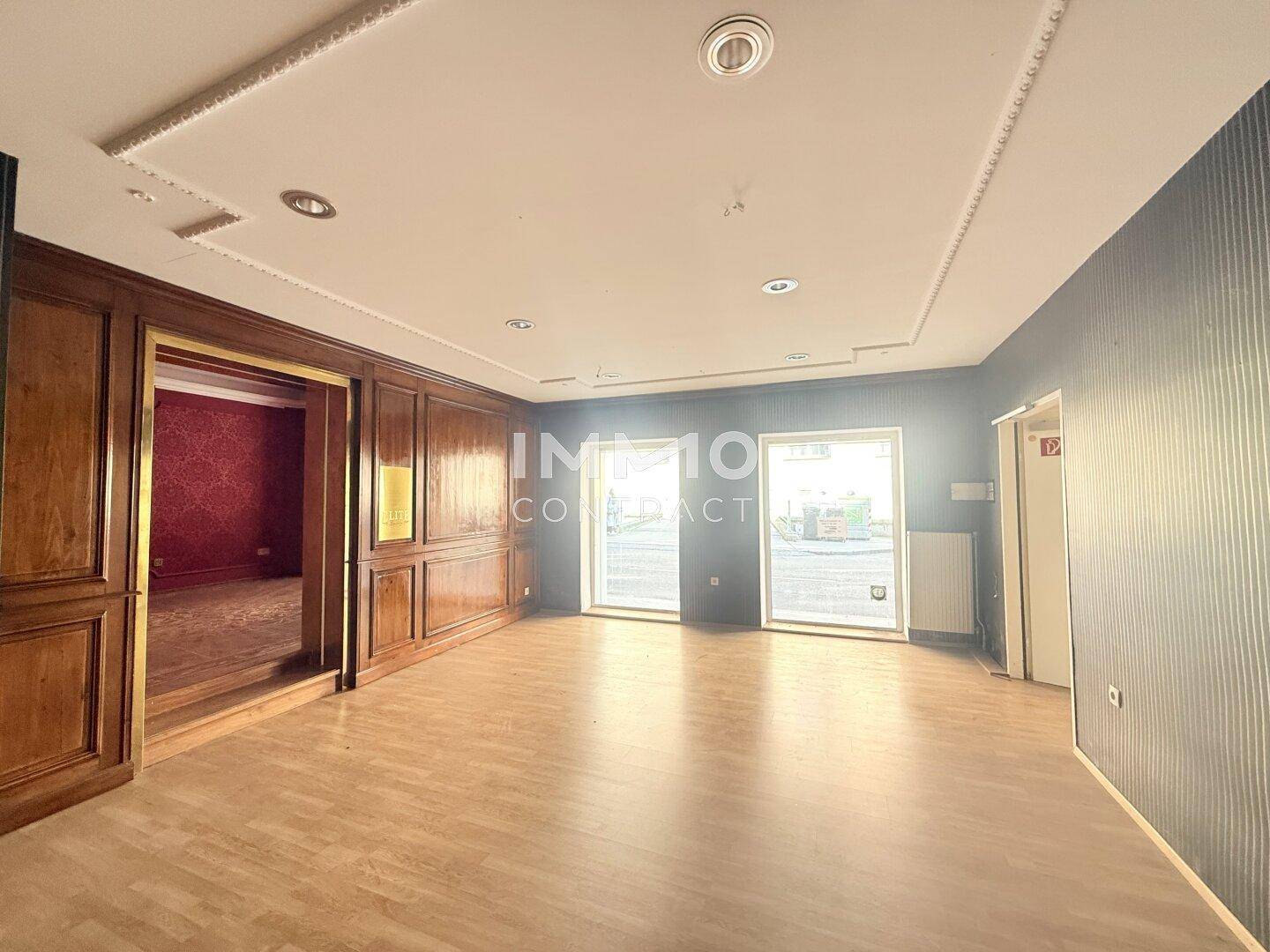 Heller Geschäftsraum mit Holztäfelung, Laminatboden und großen Fenstern zur Straße.