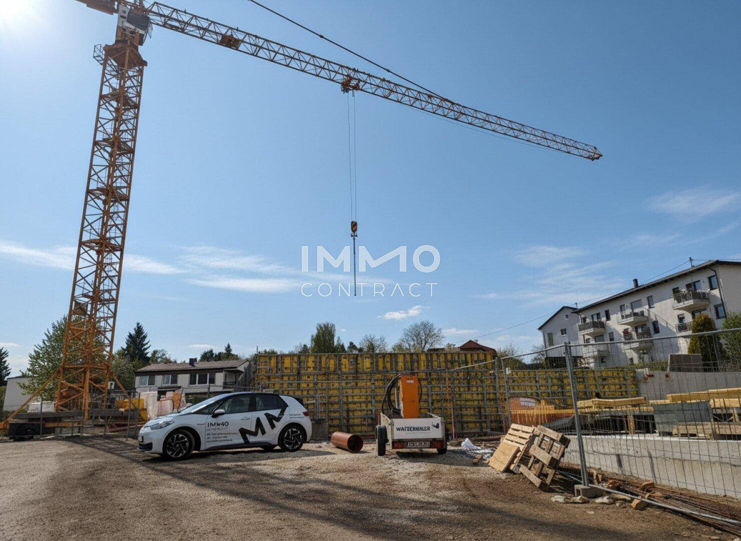 Baustelle mit großem Baukran, Schalung für Wände und umliegenden Gebäuden.