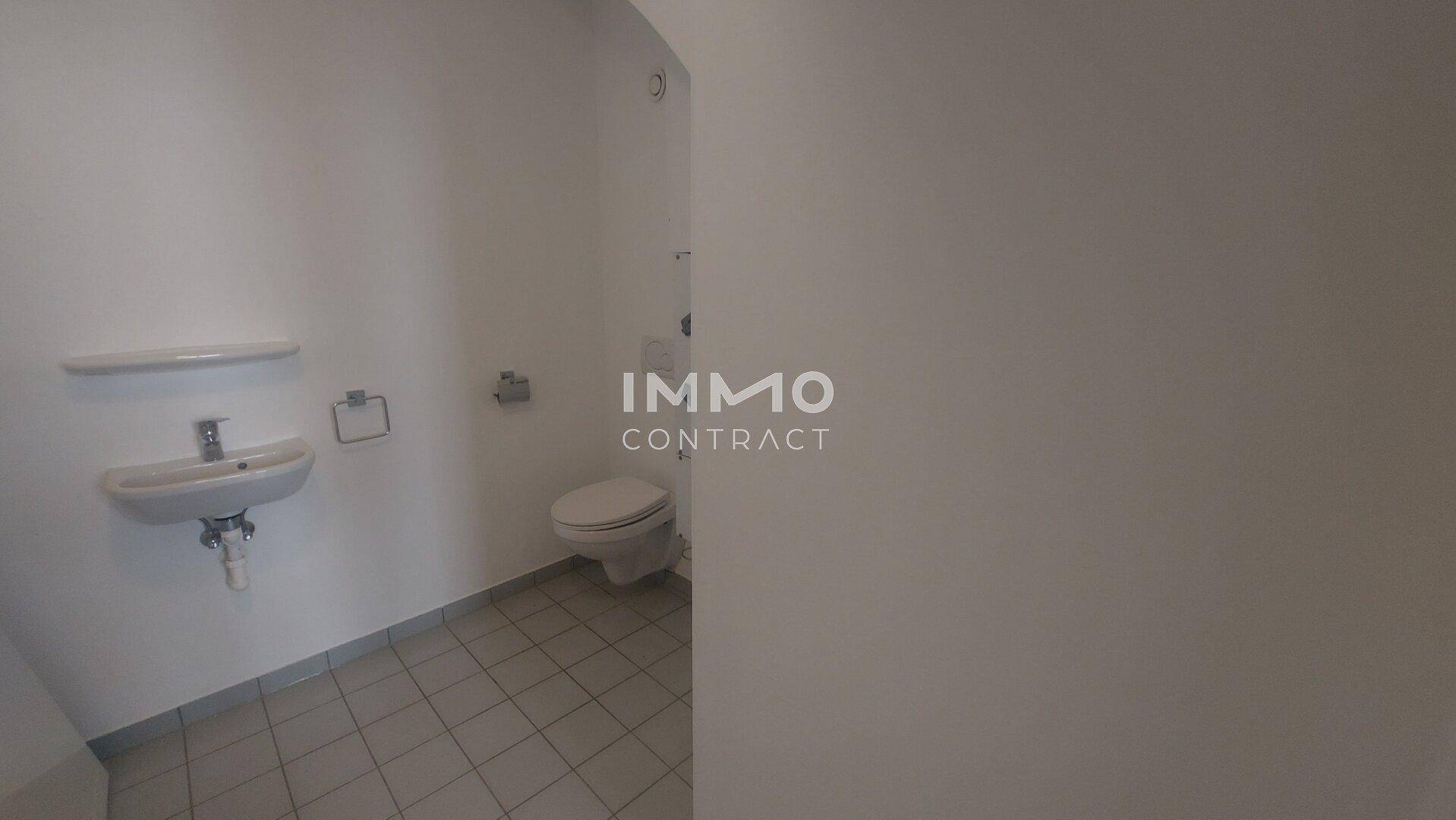 Funktionales WC mit Fliesenboden, Toilette und einem einzelnen Waschbecken.