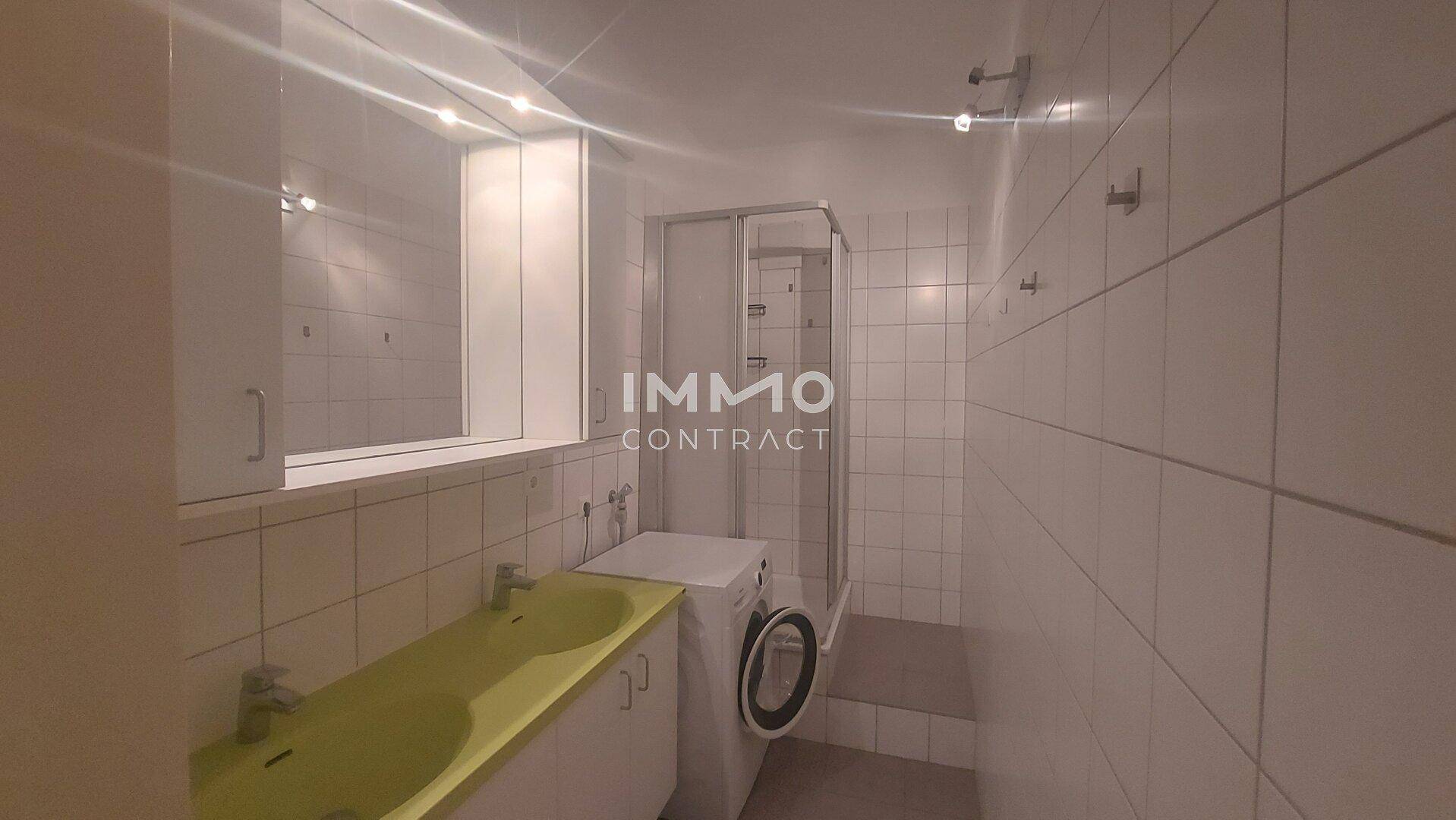 Badezimmer mit Dusche, Waschbecken und Waschmaschine.