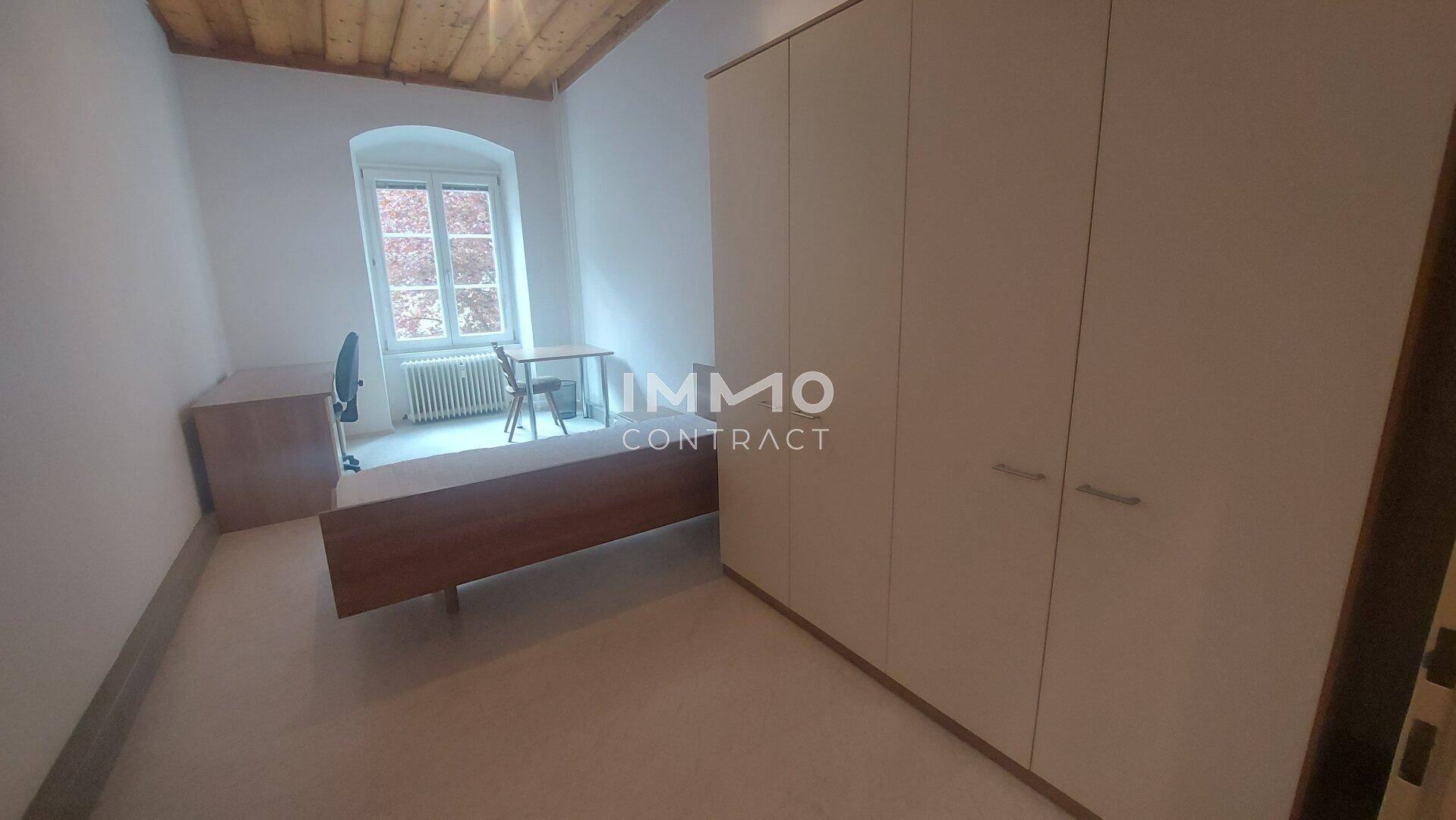 Schlafzimmer oder Arbeitszimmer mit großem Kleiderschrank und Fenster.