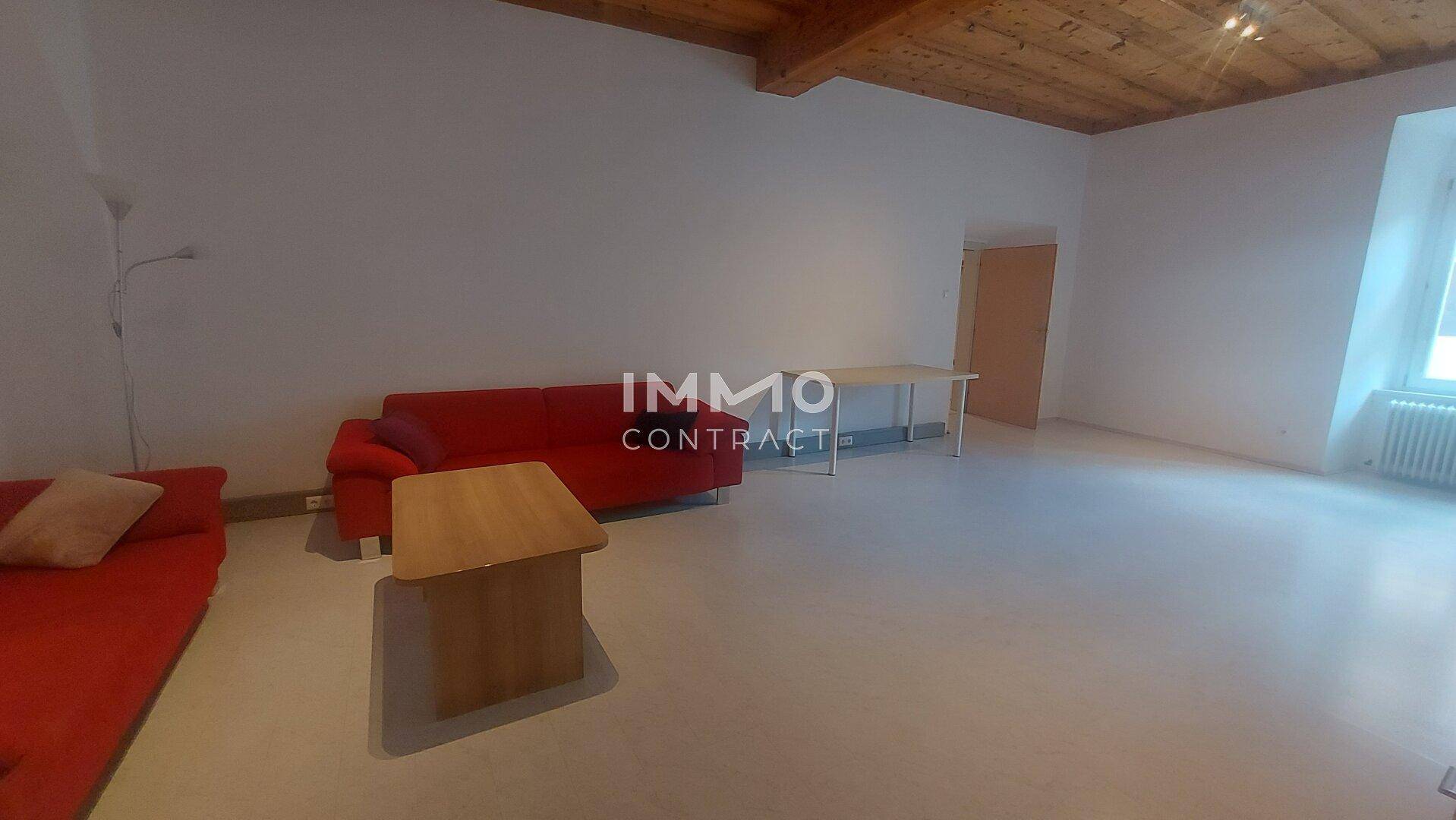 Geräumiger Wohnbereich mit Holzbalkendecke und minimalistischer Einrichtung.
