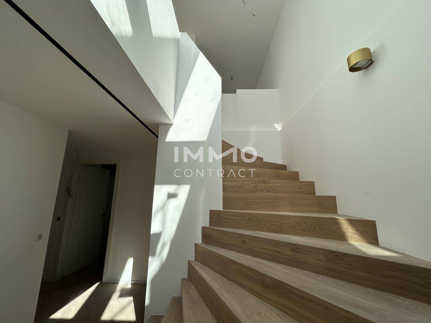 Moderne Holztreppe mit klaren Linien, die die verschiedenen Ebenen verbindet.