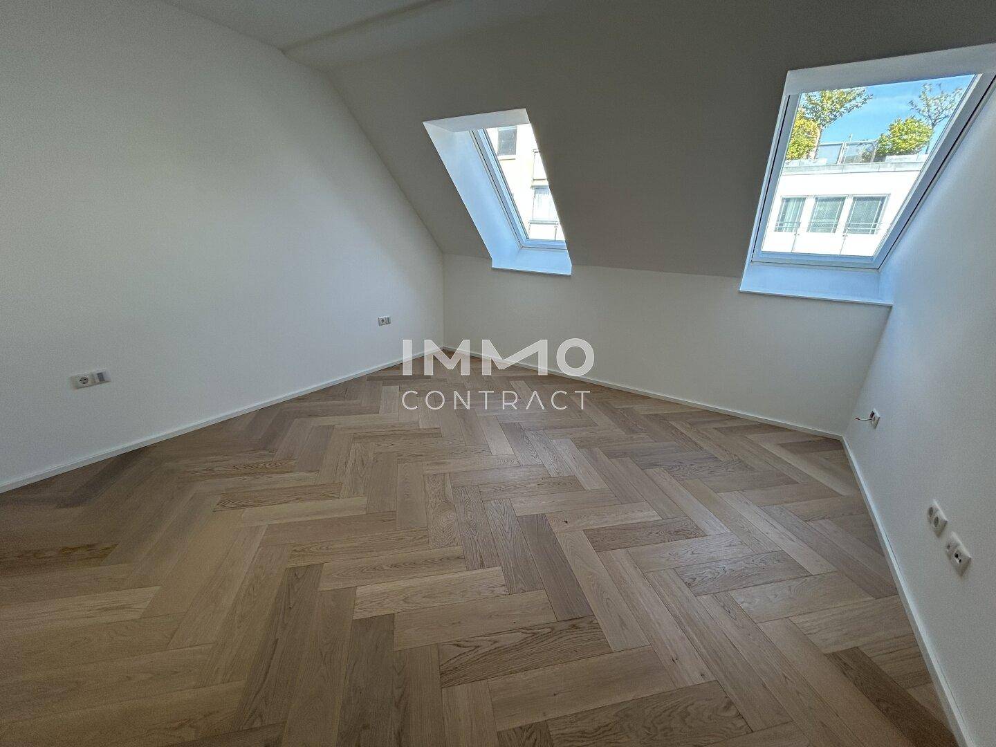 Geräumiges Schlafzimmer im Dachgeschoss mit zwei Dachfenstern und Parkettboden.