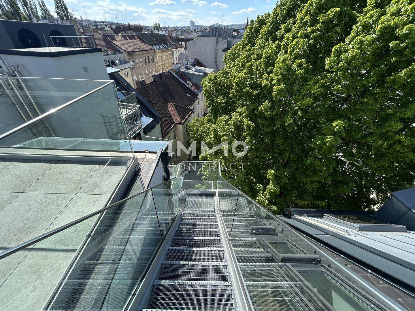 Blick von der Dachterrasse über die Stadt und die umliegenden Gebäude mit viel Grün.