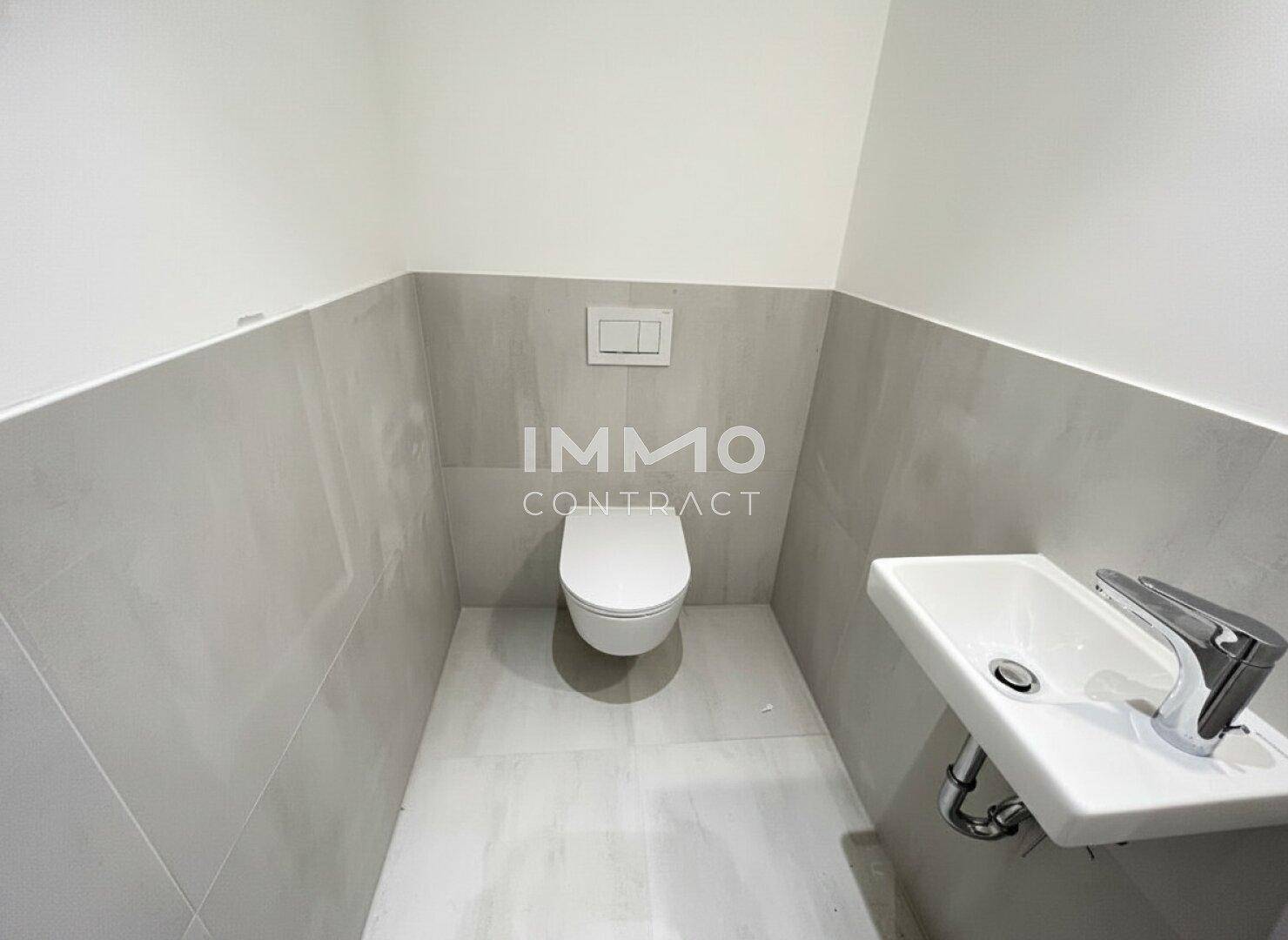 Separates Gäste-WC mit wandhängender Toilette, kleinem Waschbecken und modernen Fliesen.